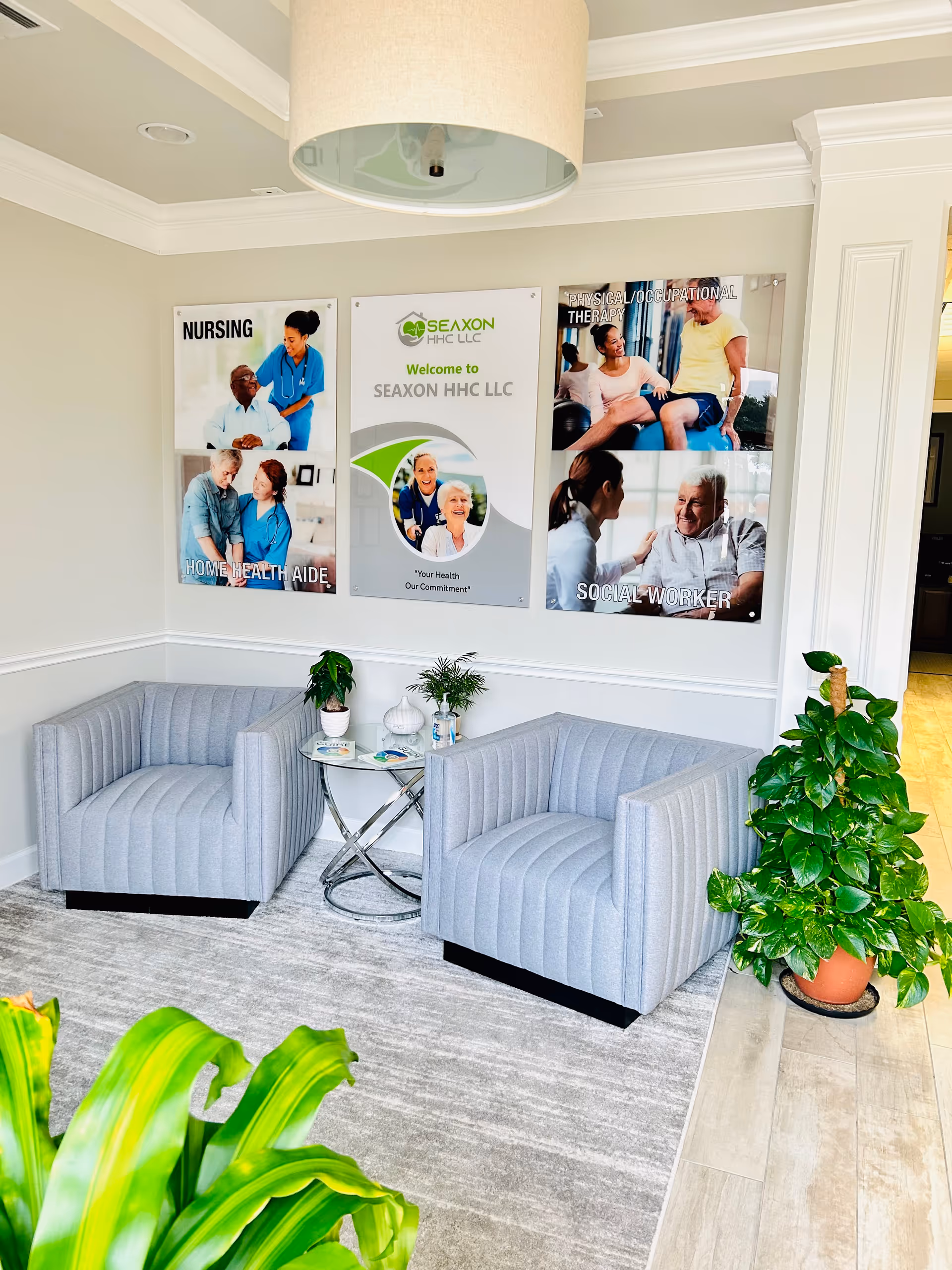 Modern waiting area with two striped chairs, a glass table, posters, and potted plants.