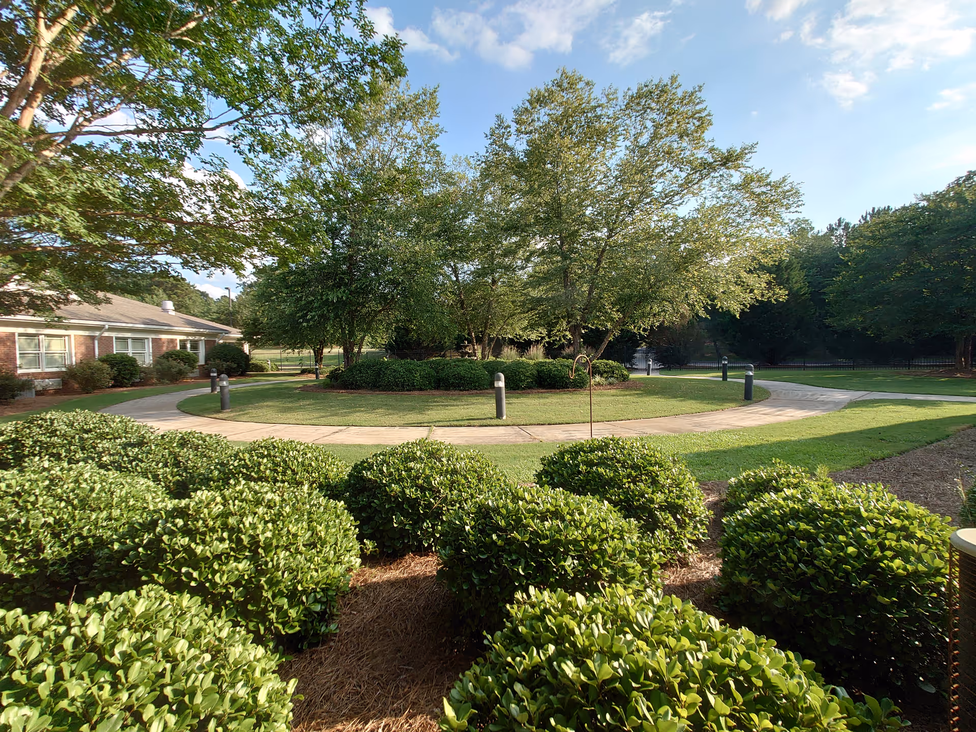 Circular driveway with manicured shrubs and trees surrounding a brick facility exterior