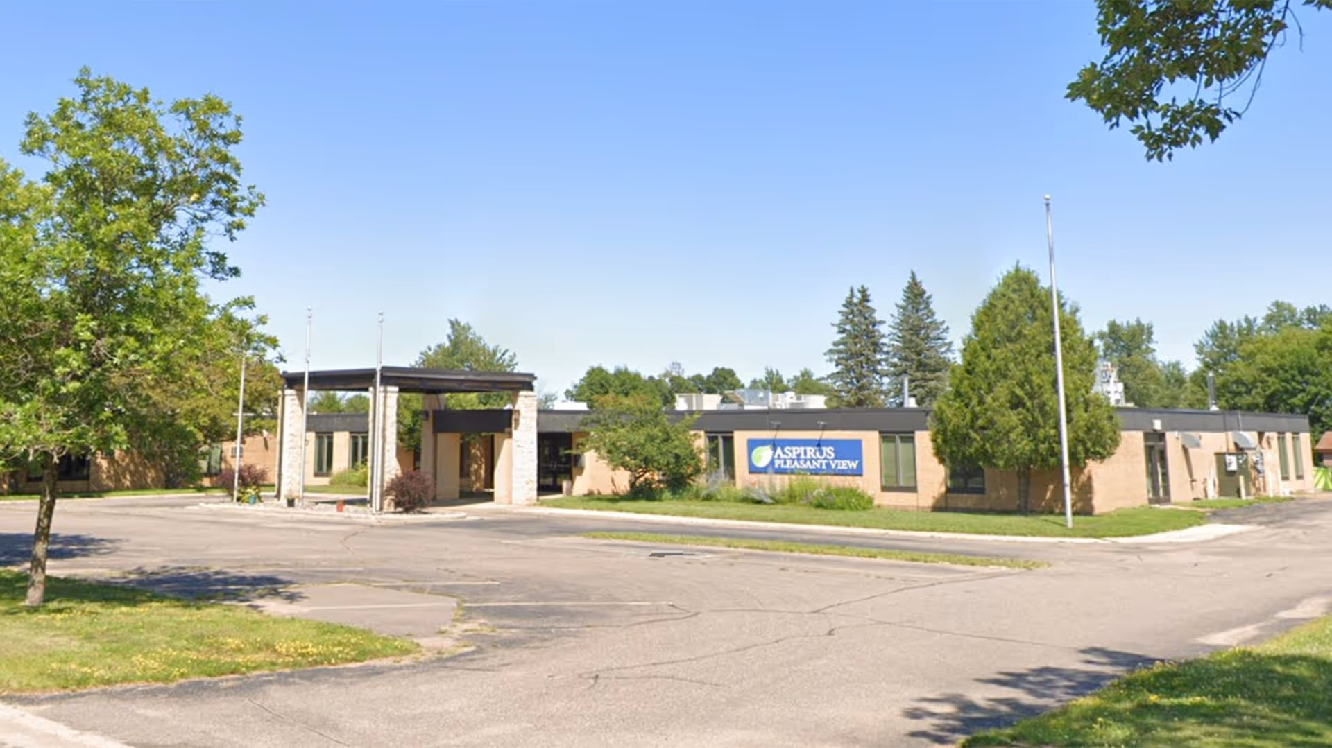 Front view of a single-story brick senior living facility with a covered entrance and sign.