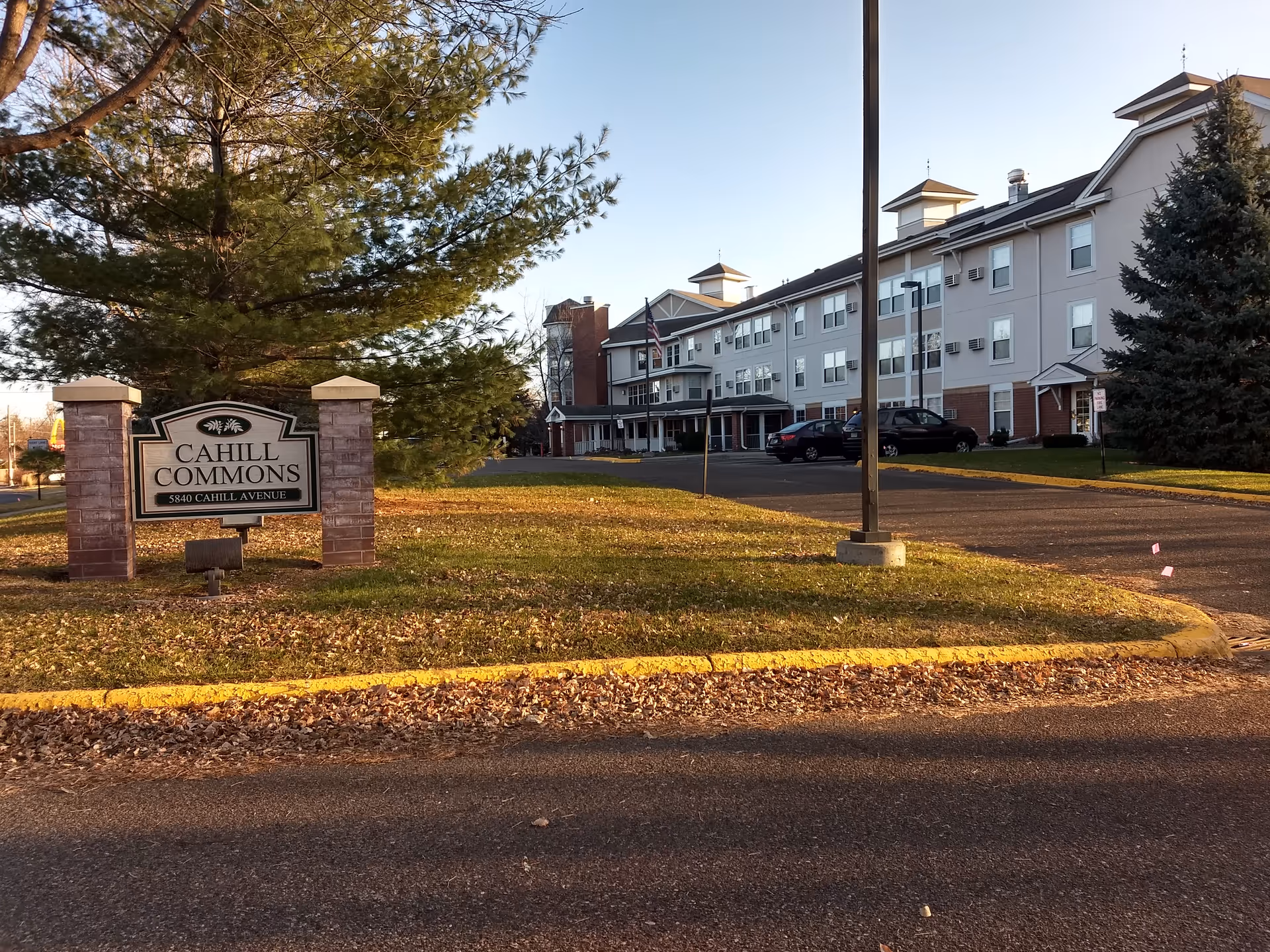 Exterior view of Cahill Commons with sign, driveway, and parked cars.