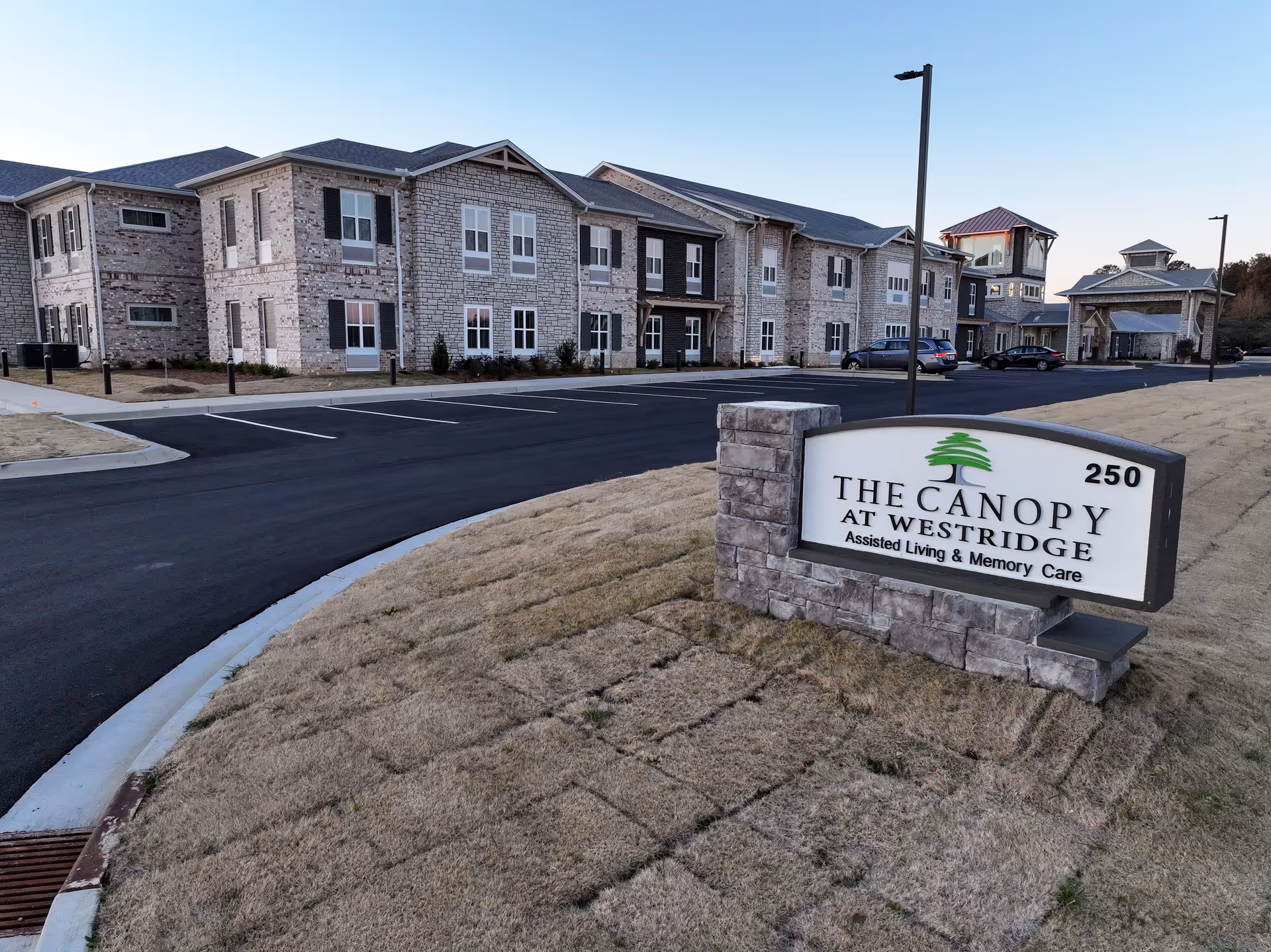 Exterior view of Canopy at Westridge senior living, showing brick buildings, sign, and parking.