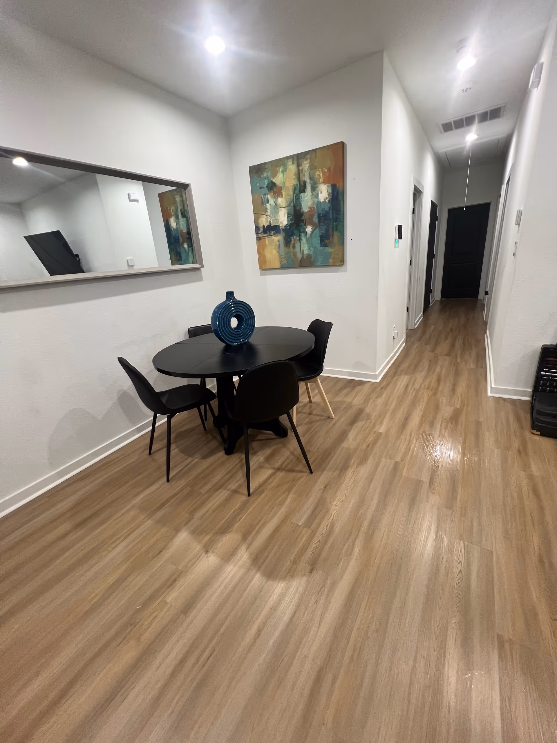 Round black dining table with four chairs in a bright, minimalist interior.