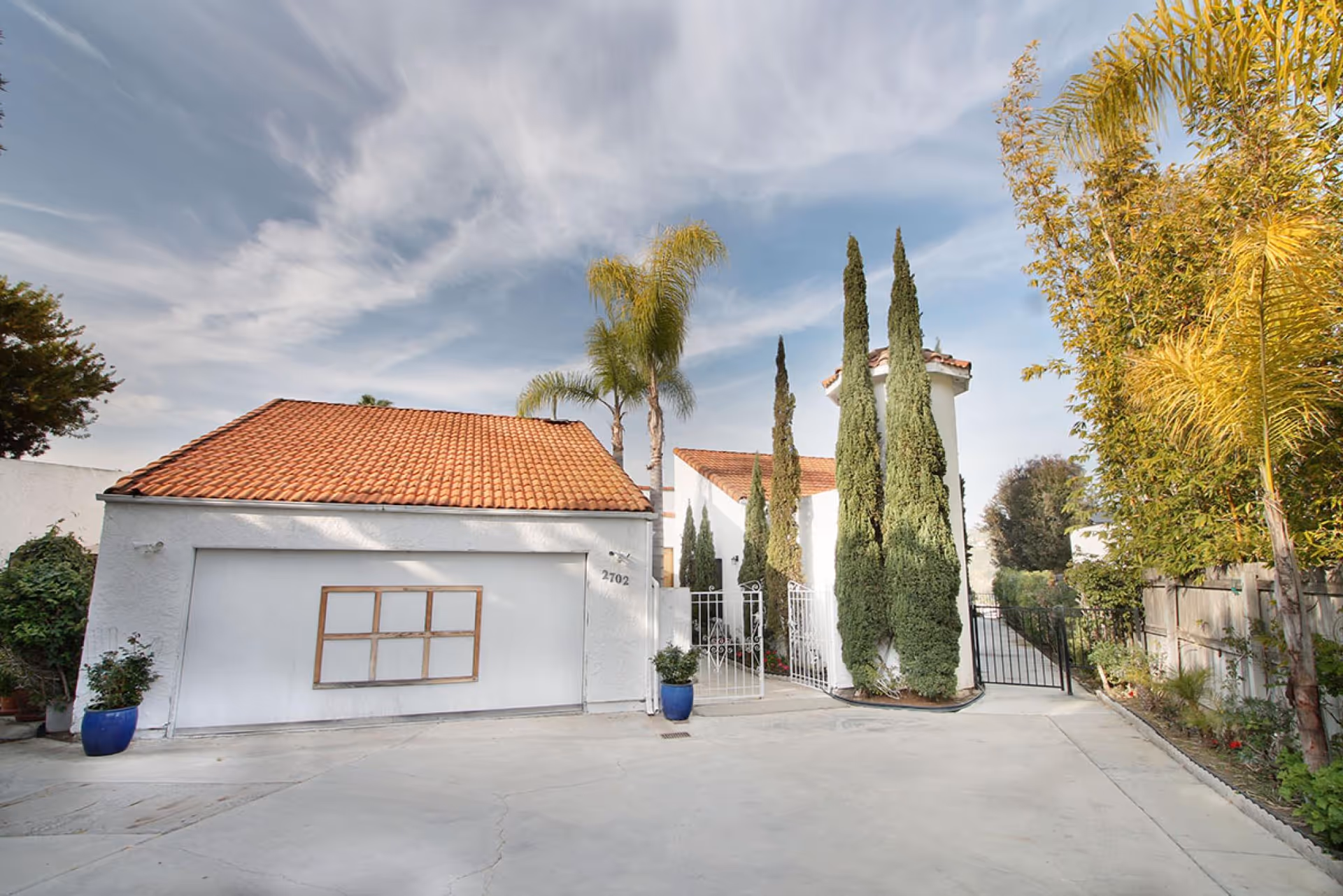 Exterior view of La Costa Golf Care RCFE entrance with white walls, red-tiled roof, and gates.