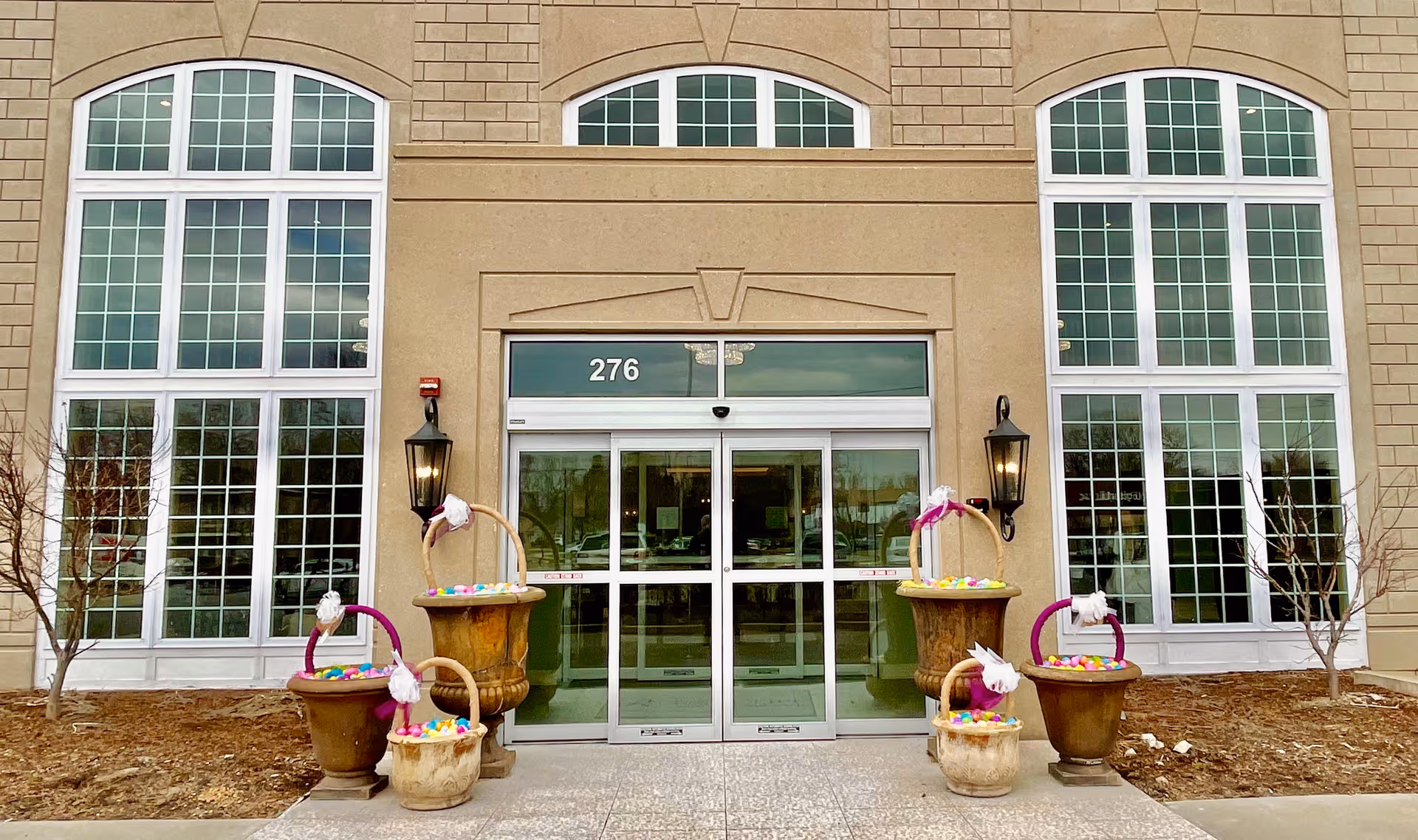 Broad glass entrance at The Radcliff with large arched windows and decorative planters.