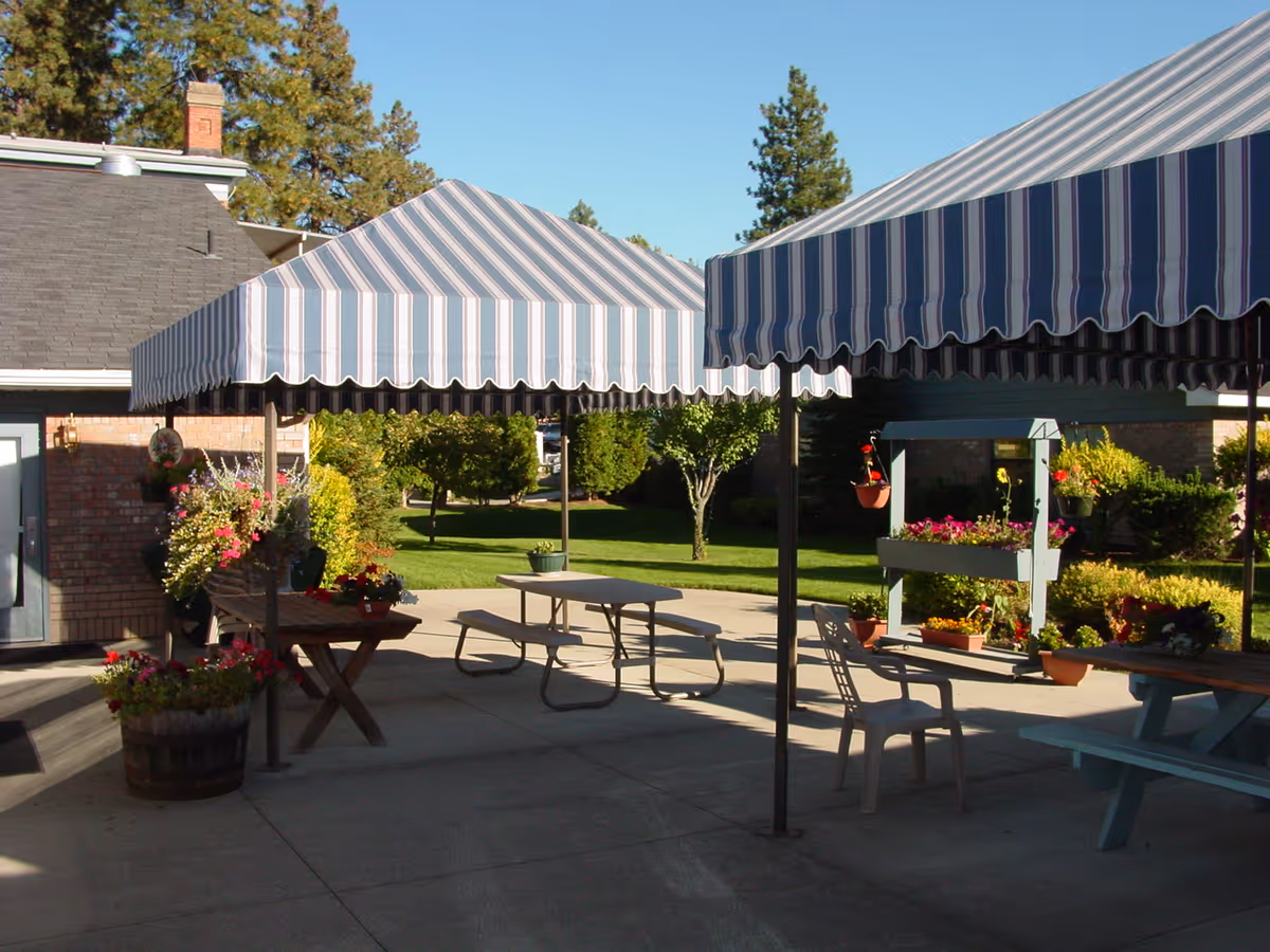 Outdoor patio at Sunshine Health & Rehab with striped canopies and planters.