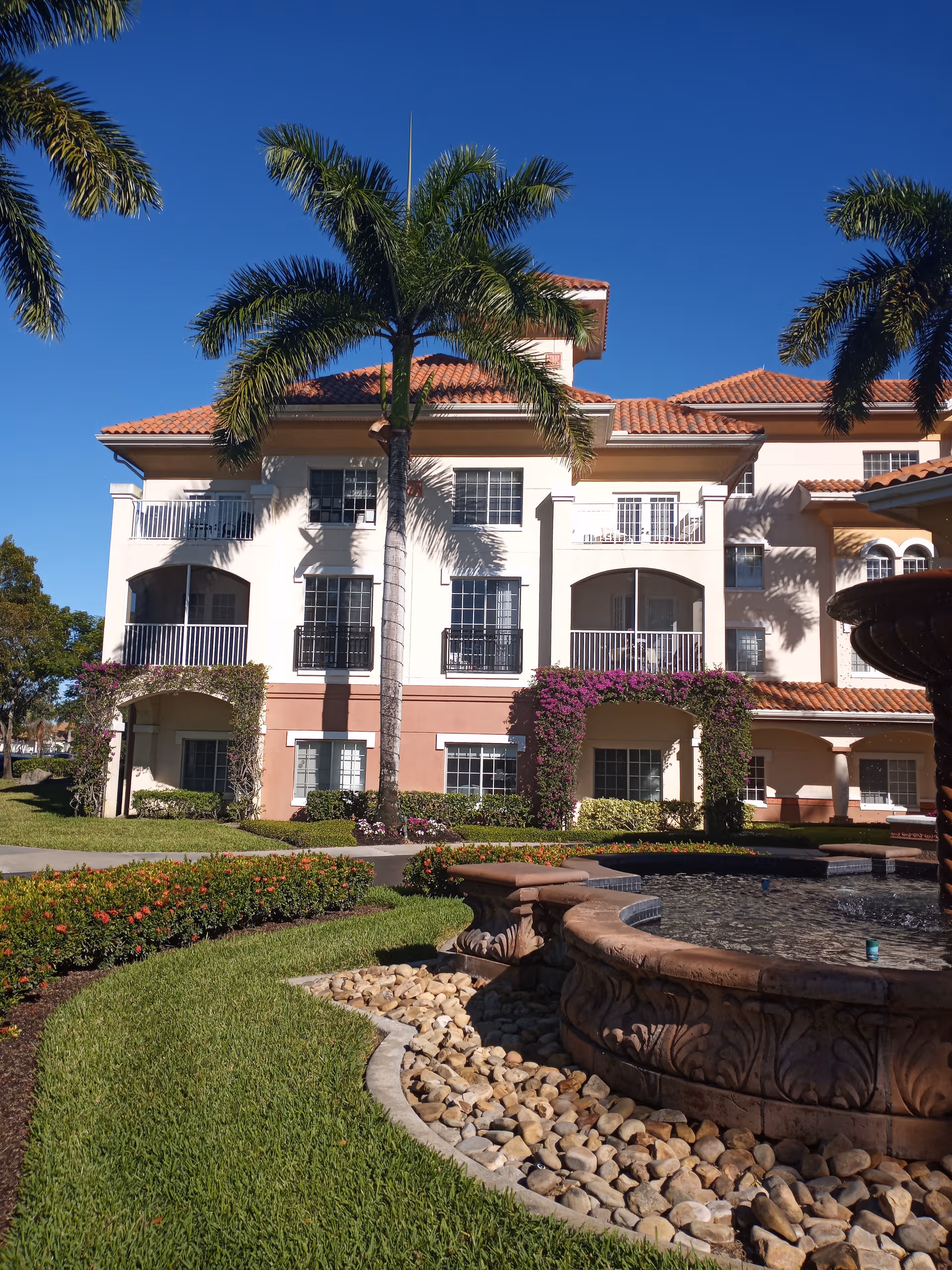 Villa at Terracina Grand exterior with palm trees and a fountain.