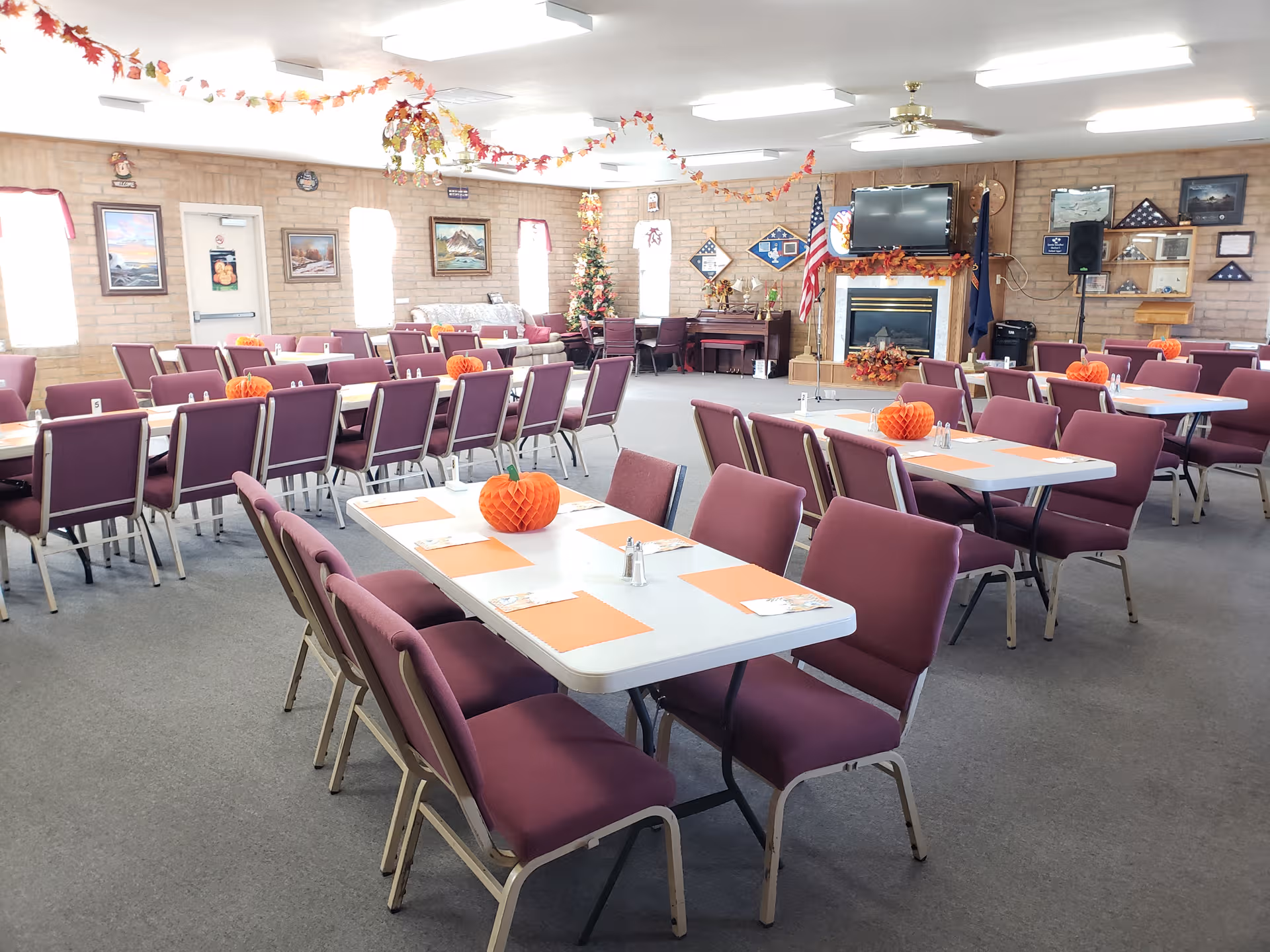 A large senior living facility dining hall with purple chairs and autumn decorations.