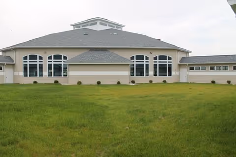 A single-story Sunshine Gardens senior living facility with large arched Windows and a green lawn.
