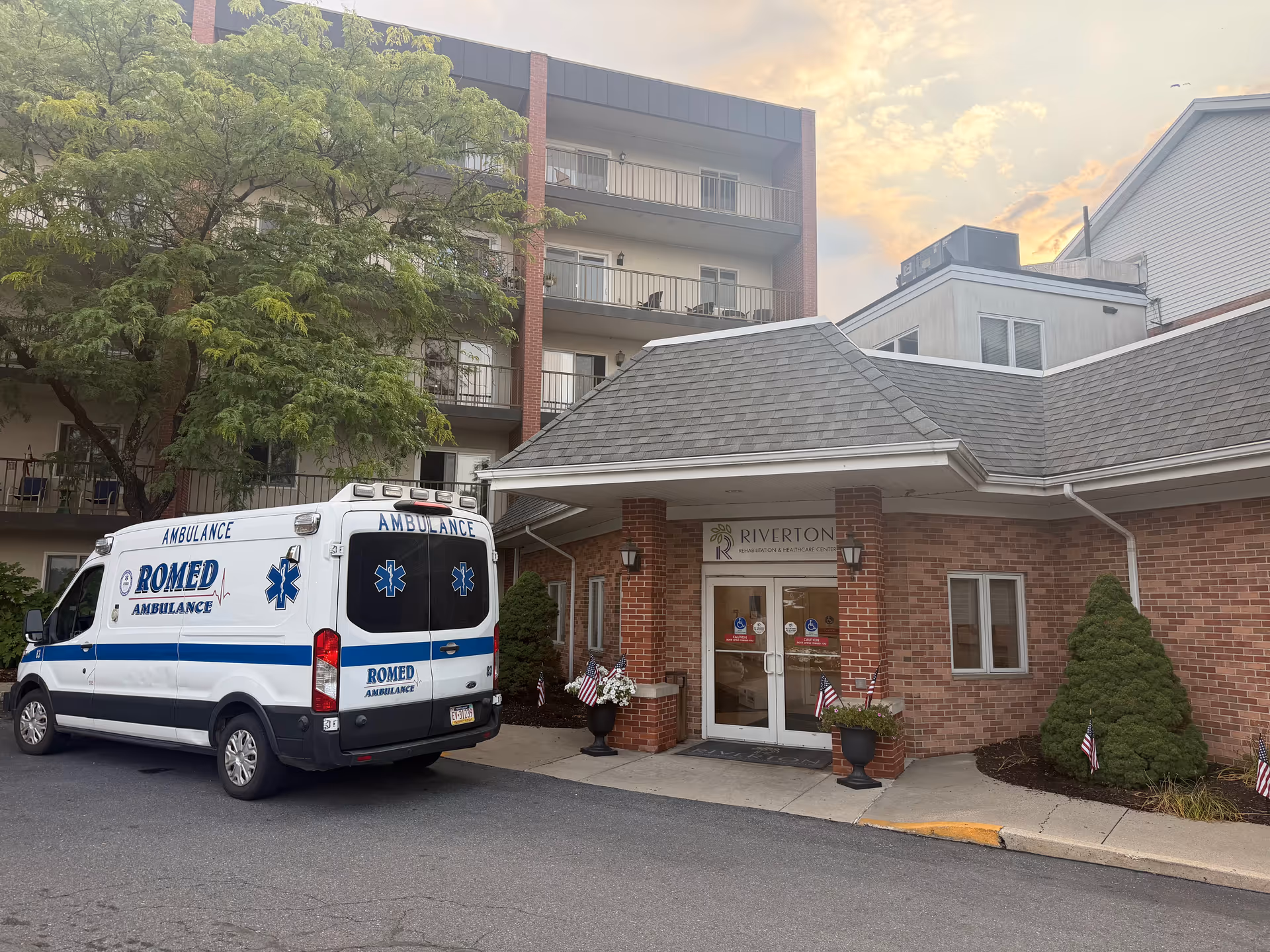 Ambulance parked outside the Riverton Enhanced Senior Living entrance beside brick building.