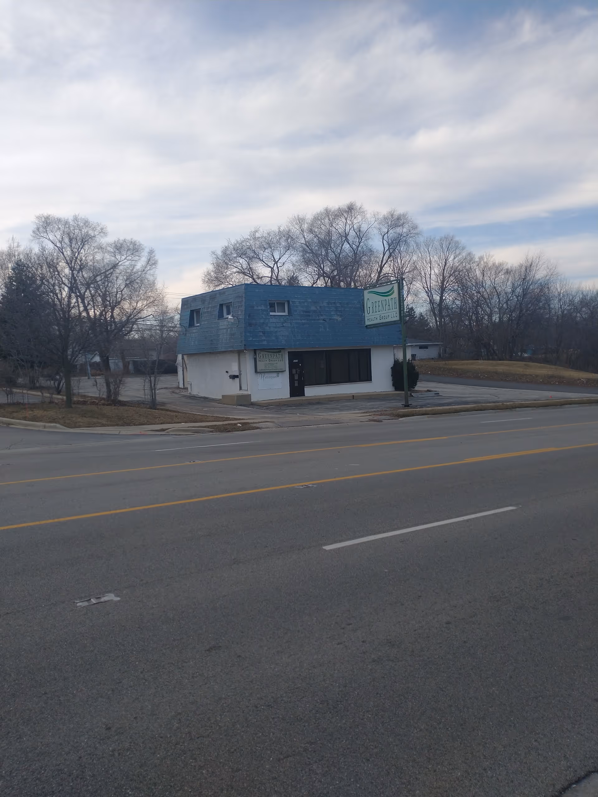 Blue-roofed senior care facility on a street with leafless trees.