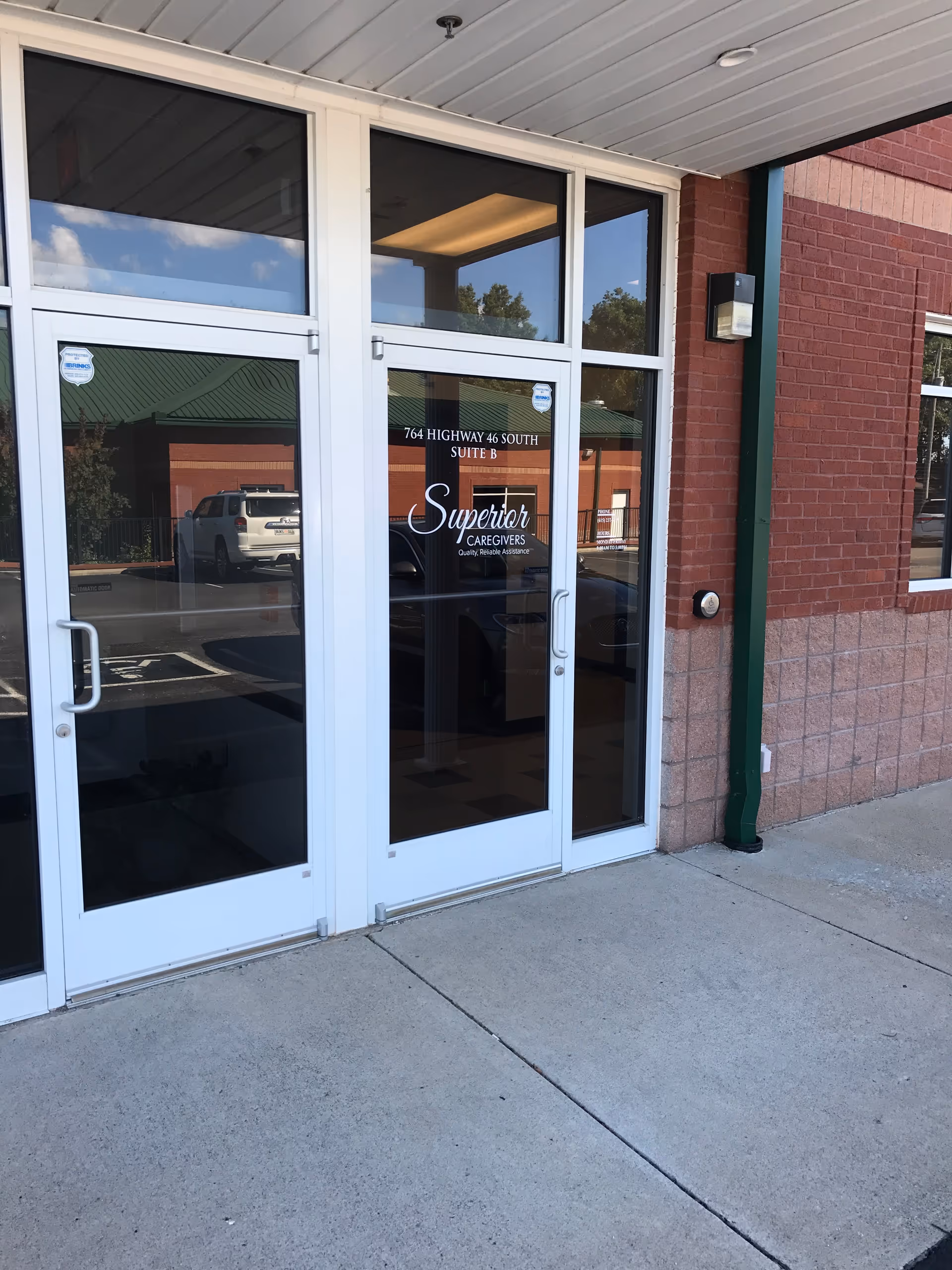 Glass entrance doors with Superior Caregivers sign, brick exterior, and a sidewalk.