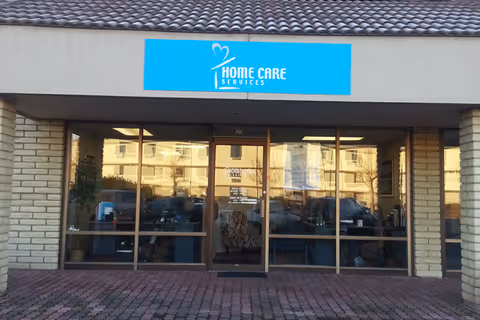 Front view of a storefront with a blue Home Care Services sign above glass doors.