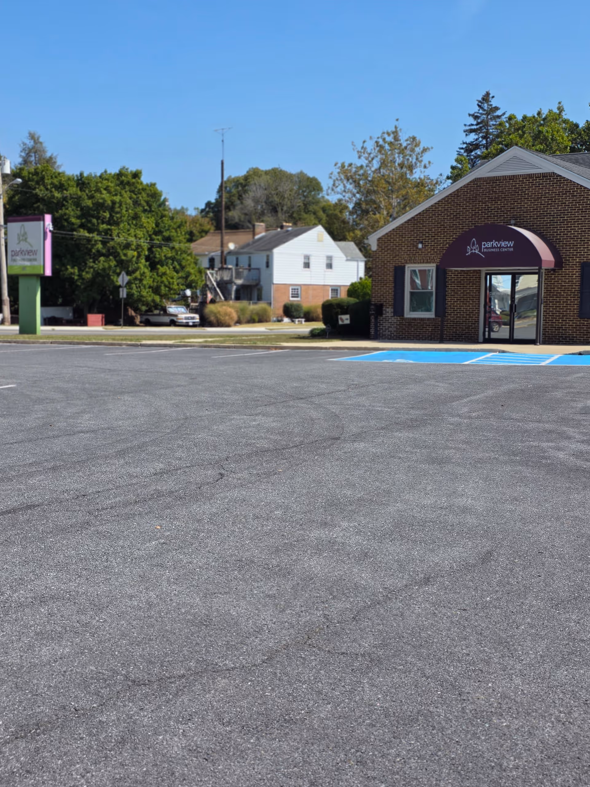Exterior view of a brick facility with purple awning and parking lot.