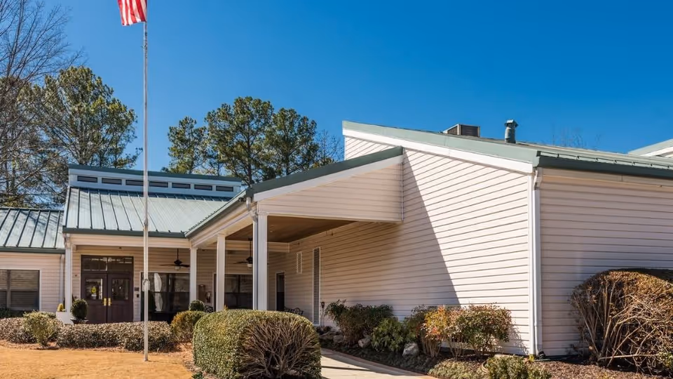 Front exterior of Legacy Marietta facility with covered entrance, flagpole, and manicured shrubs.
