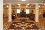 Spacious indoor common area with seating, pillars, a fireplace, and decorative rug.