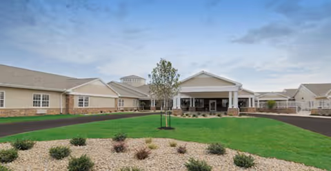 Bailey Woods senior living facility front entrance with green lawn and landscaped rock beds.