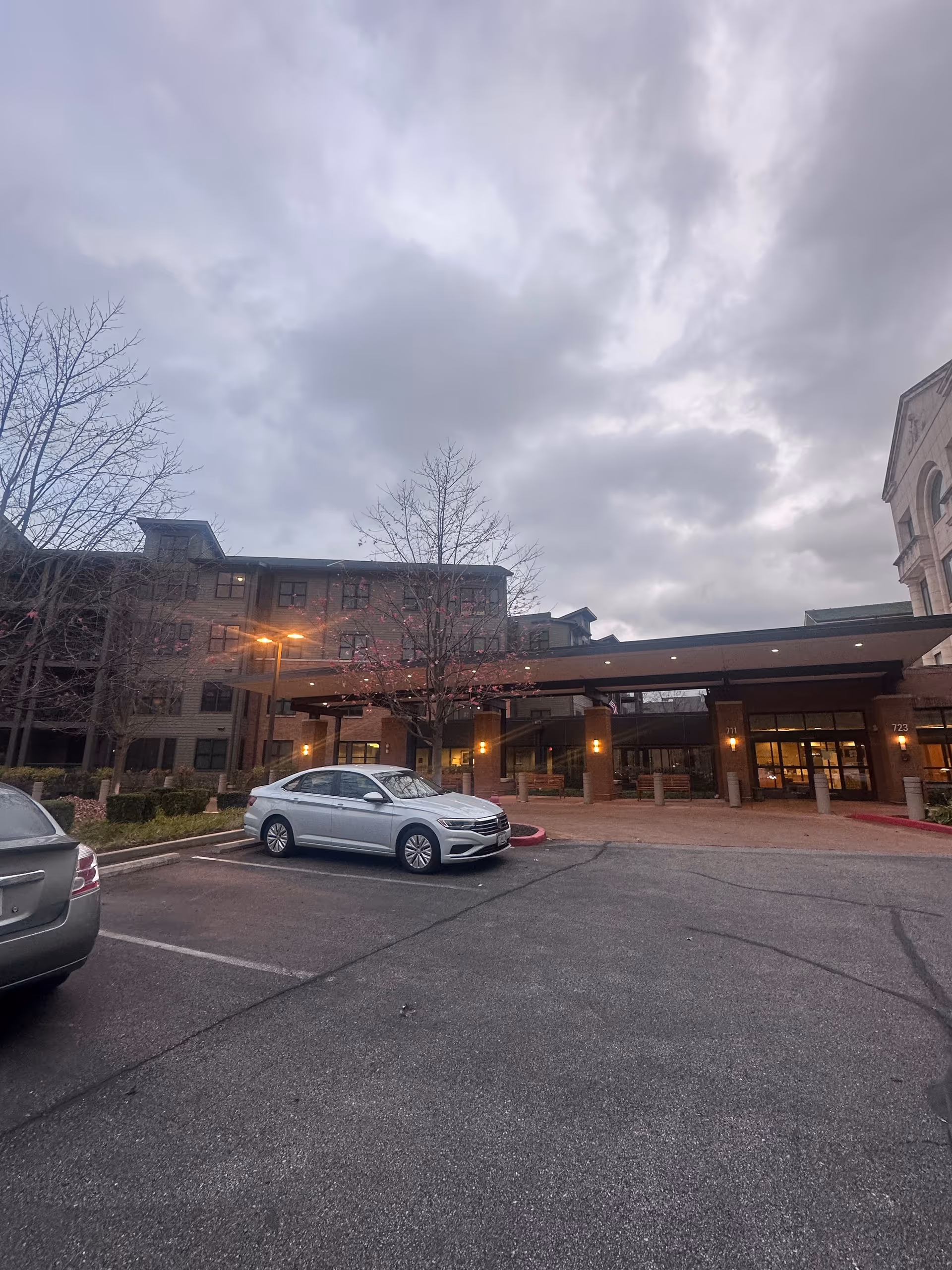 Front entrance of the Lutheran Convalescent Home with parked cars under a cloudy sky.