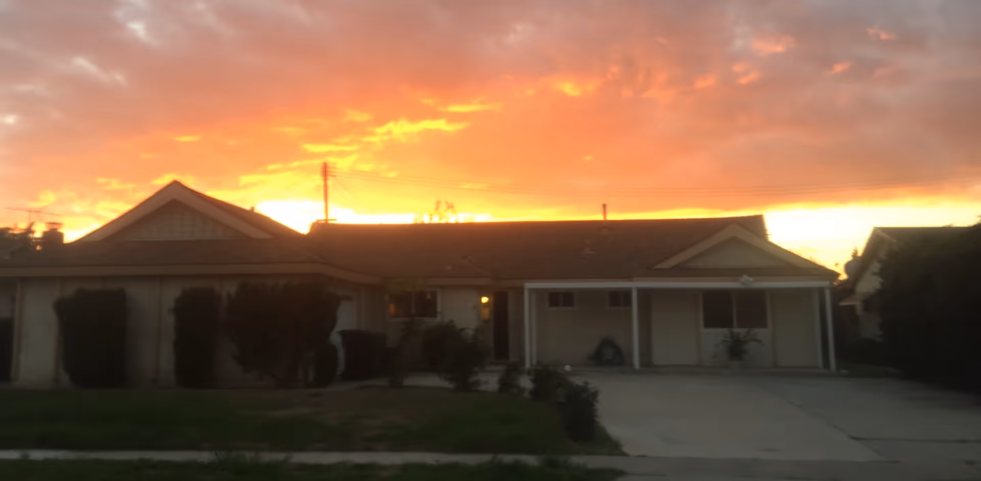 Sunset over a single-story building with a covered front porch and driveway