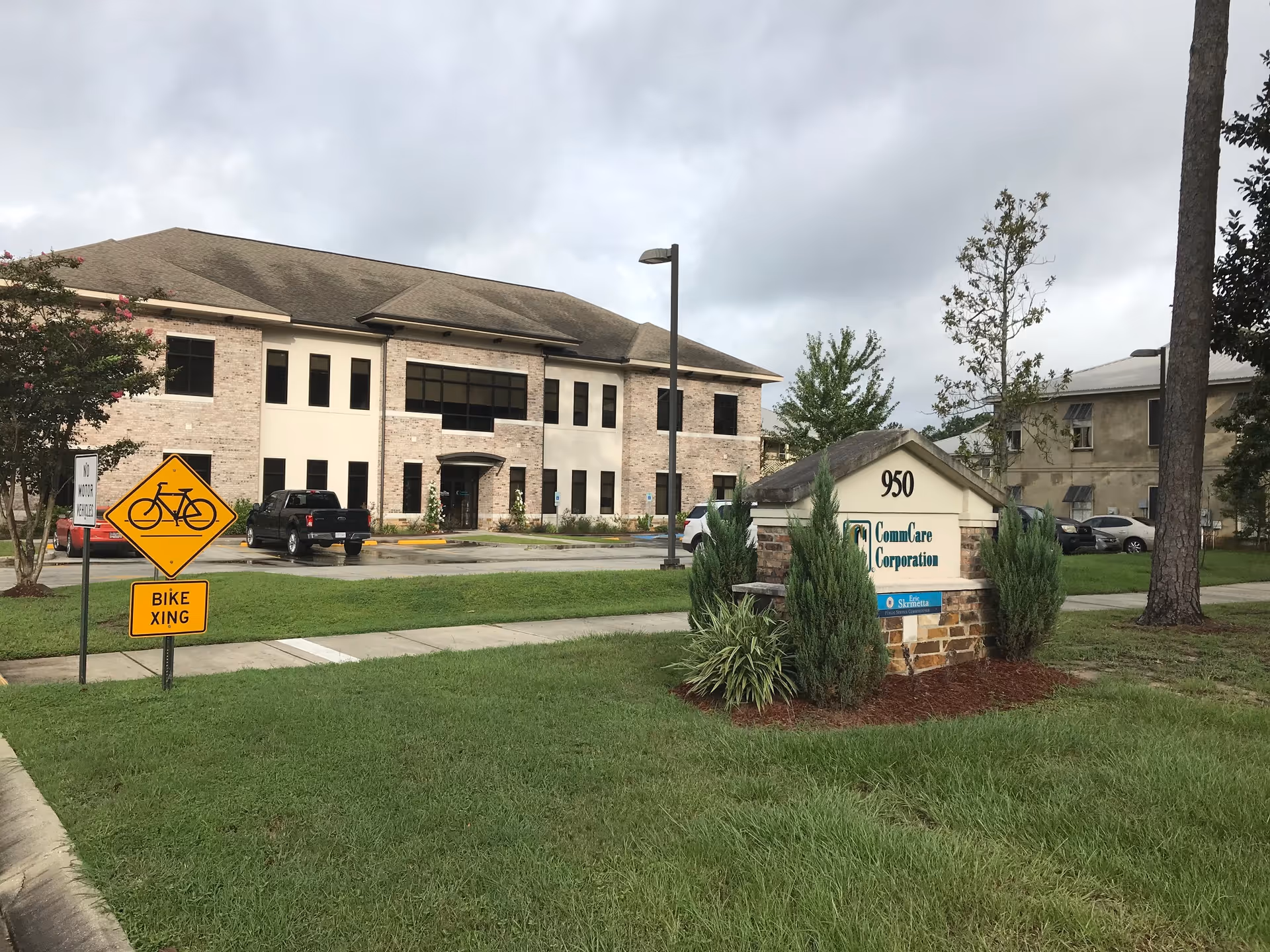 Exterior view of CommCare Corporation senior living facility with sign and bike crossing sign