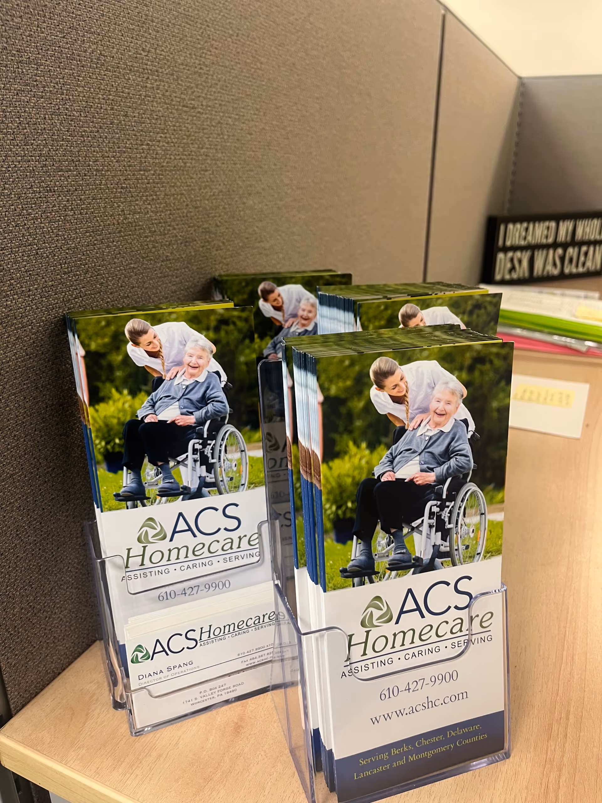 ACS Homecare brochures in clear holders on a desk inside a facility's office area.