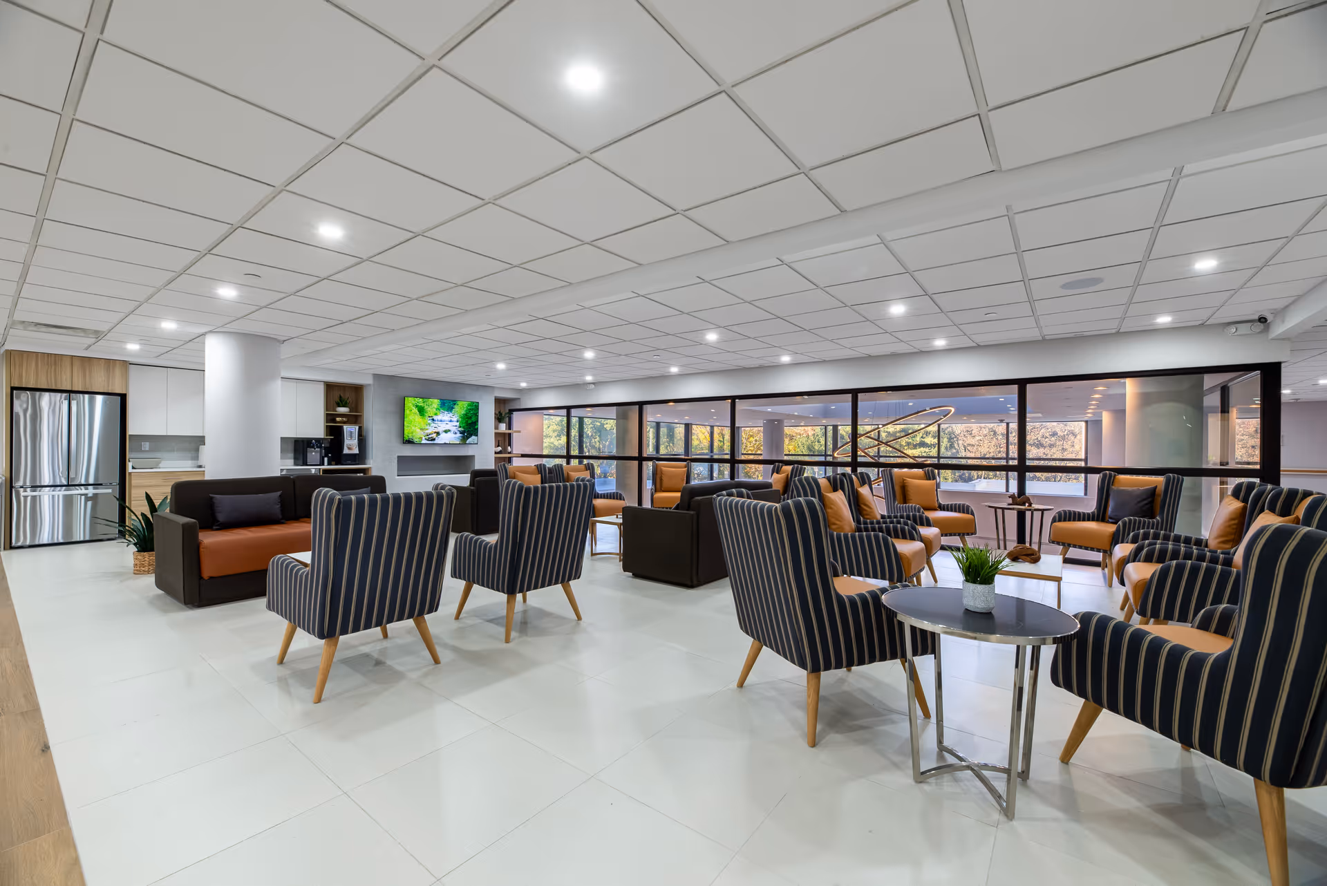 Spacious modern lounge with striped chairs, couches, tables, and large windows.