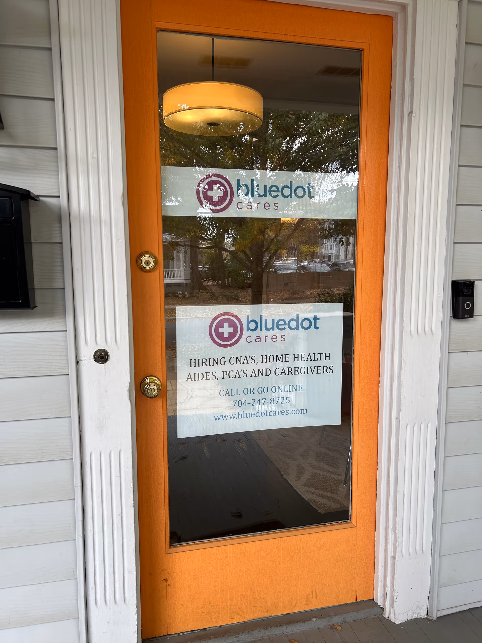 Orange-framed glass door with BlueDot Cares signs at a facility entrance.
