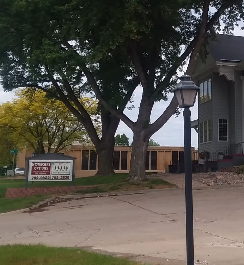 Exterior view of Homecare Options facility with trees, a sign, and a street lamp.