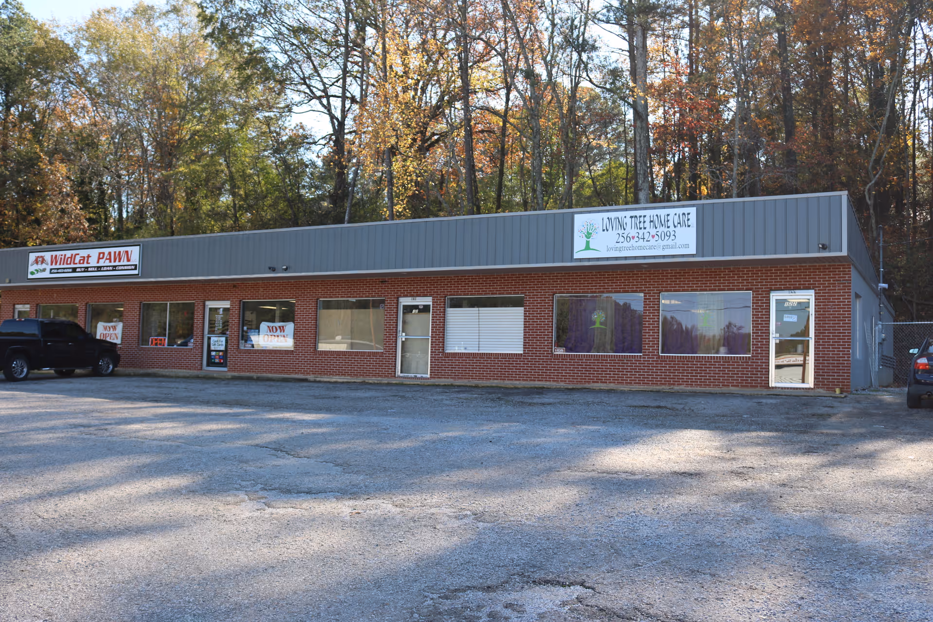 Brick, single-story storefront with large windows and a Loving Tree Home Care sign.