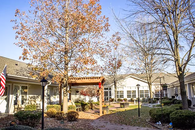 Exterior view of Brookdale Clarksville courtyard with trees, walkway, and a covered entryway.
