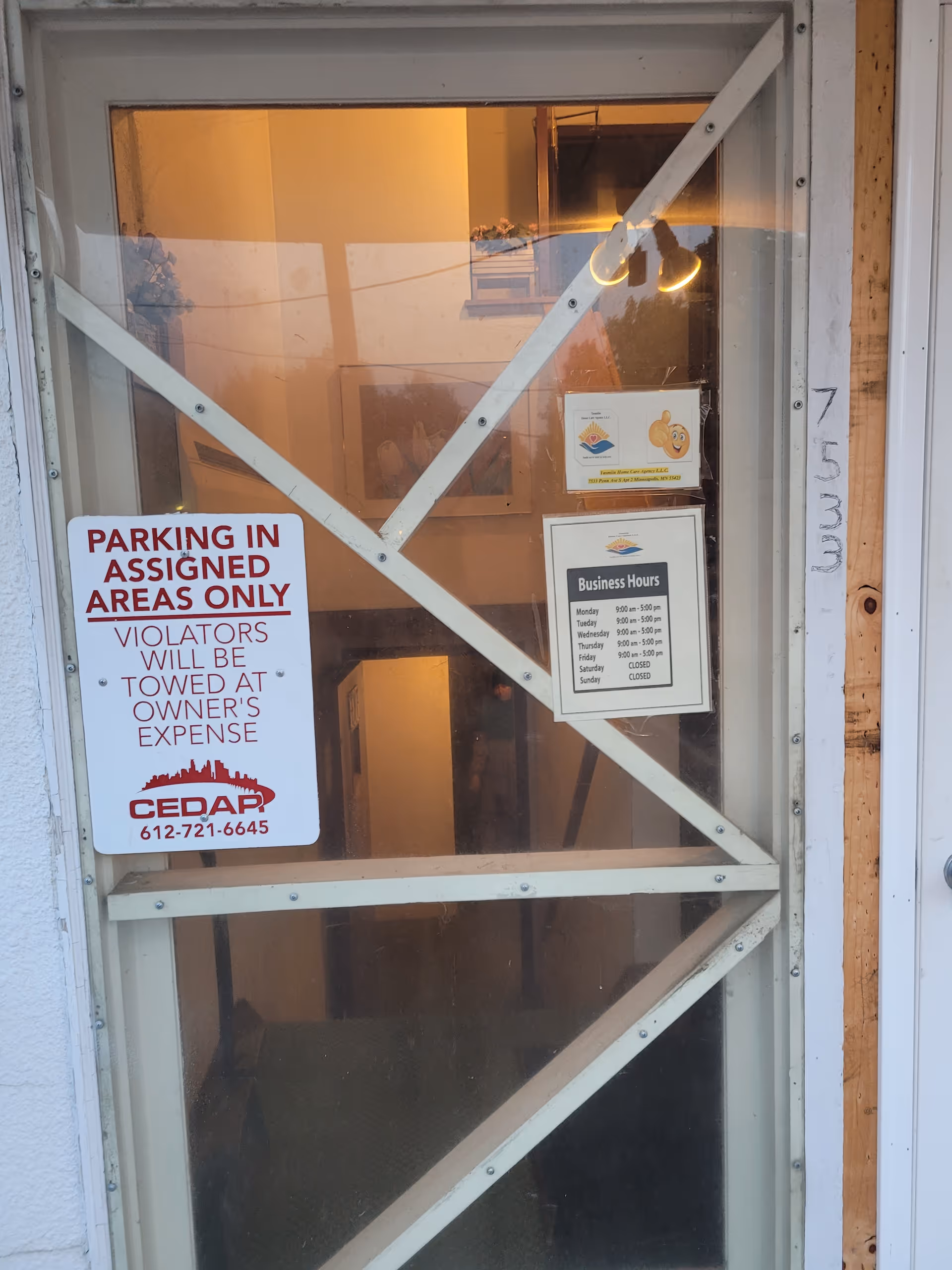 Exterior entrance door with parking sign and business hours posted.