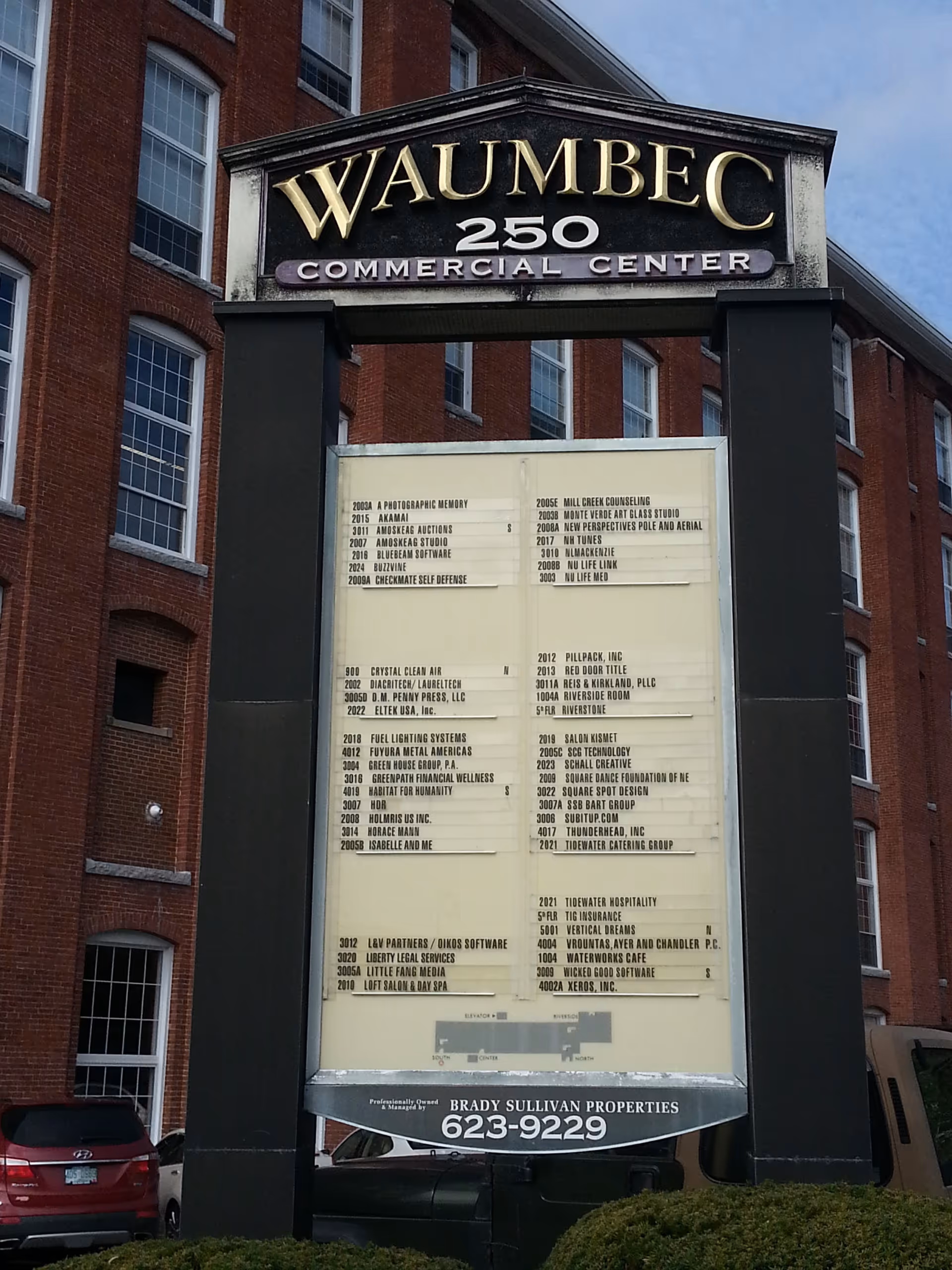 Exterior brick building with a large directory sign at the entrance.