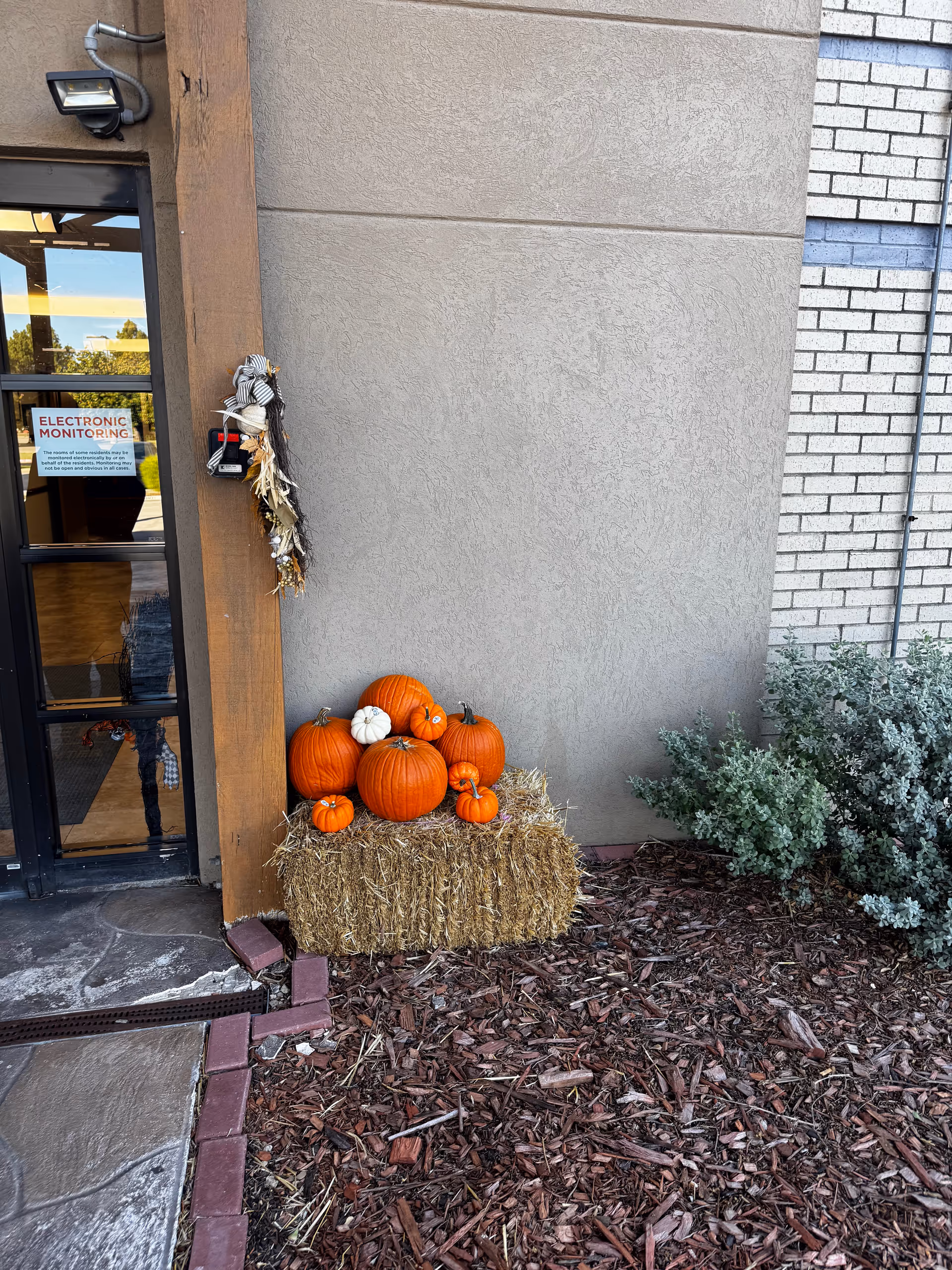 Exterior entryway with pumpkins on a hay bale near mulch