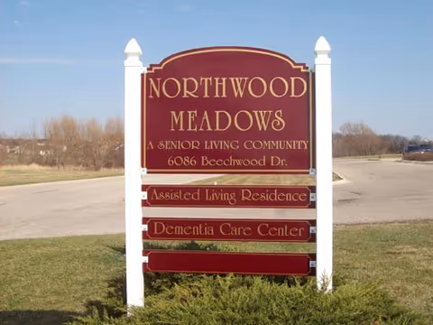 Signboard for Northwood Meadows senior living community set in a grassy lot under blue sky