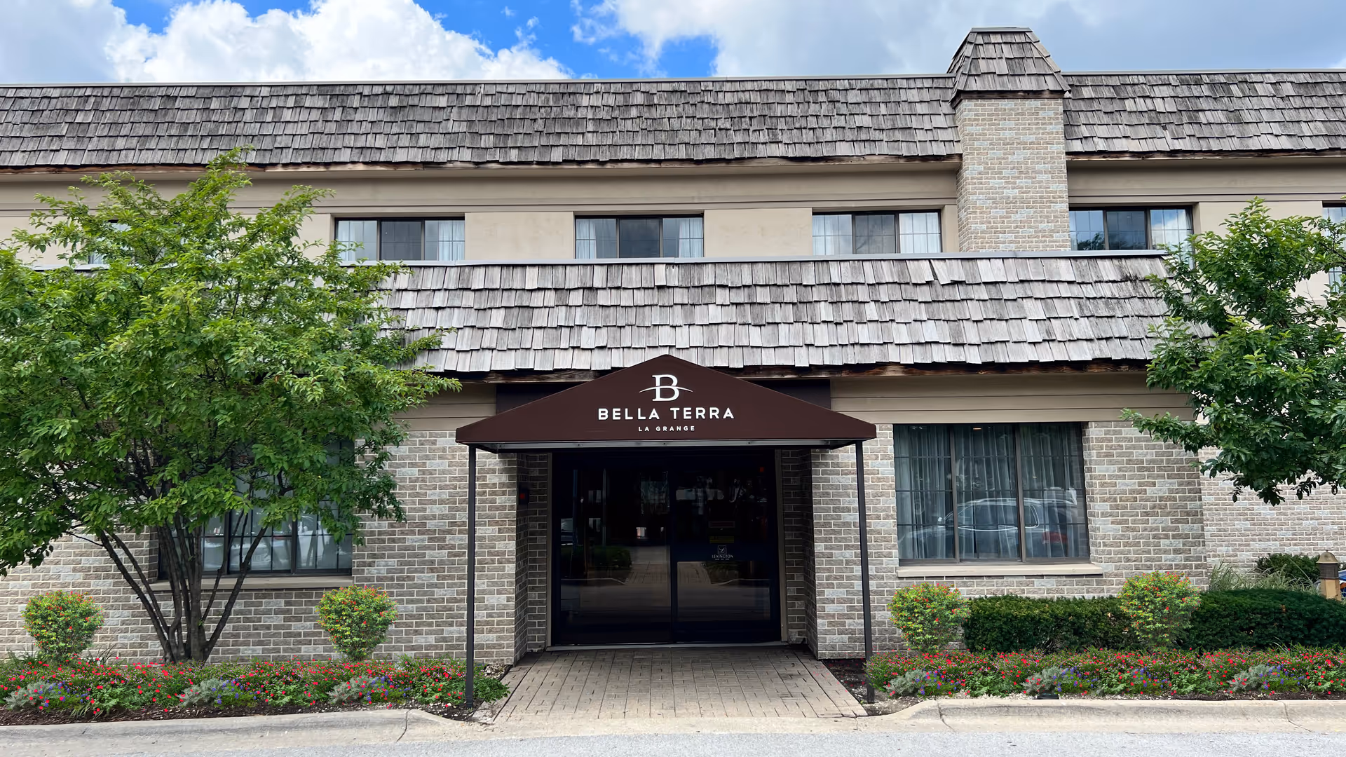 Exterior view of Bella Terra Lagrange entrance with brick building and landscaped shrubs