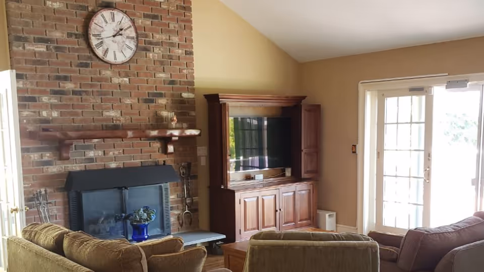 Cozy living room with brick fireplace, wooden TV cabinet, and glass doors.