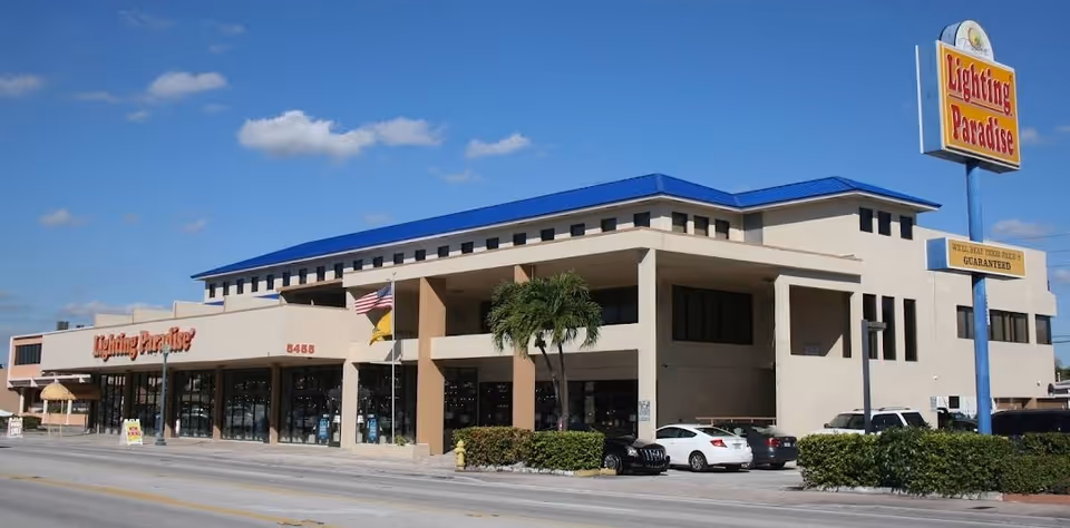 Exterior view of a beige commercial building with a blue roof and Lighting Paradise sign.