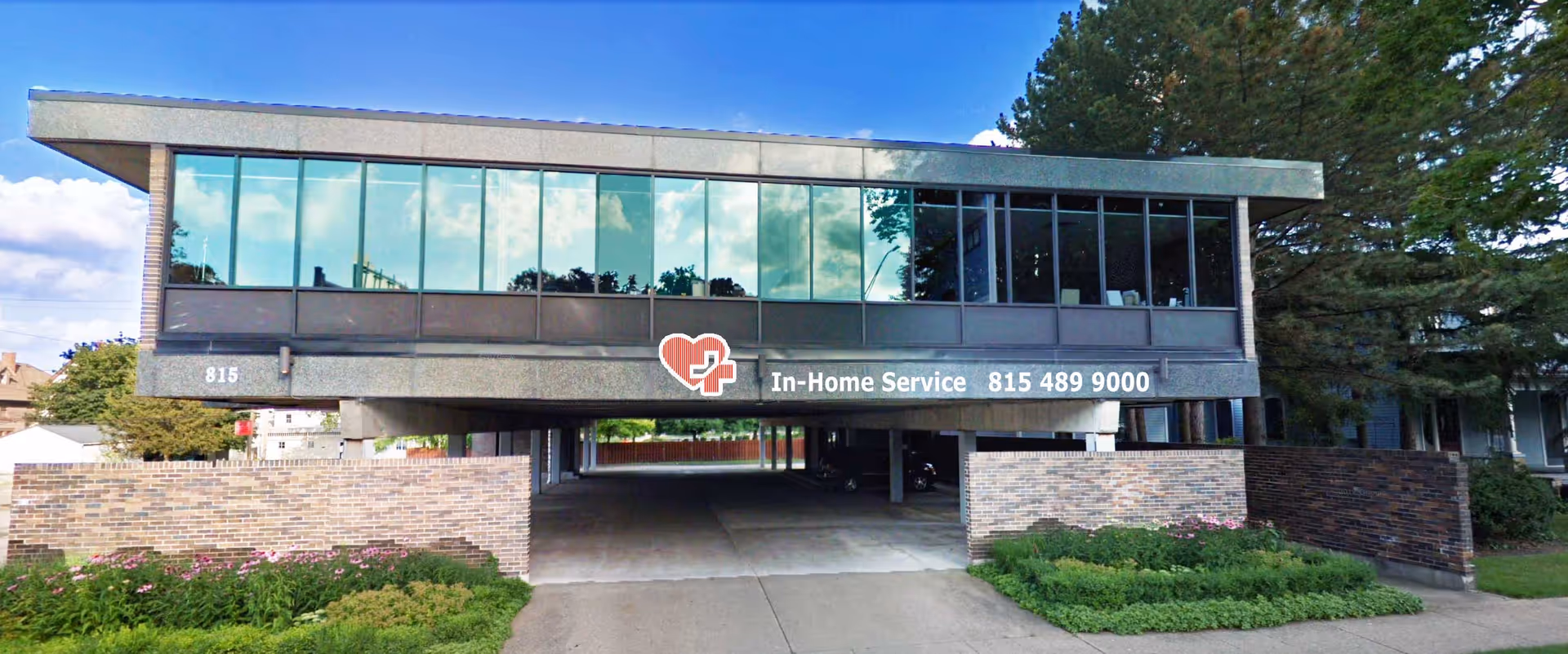 Two-story modern building with large glass windows and a sign reading In-Home Service.