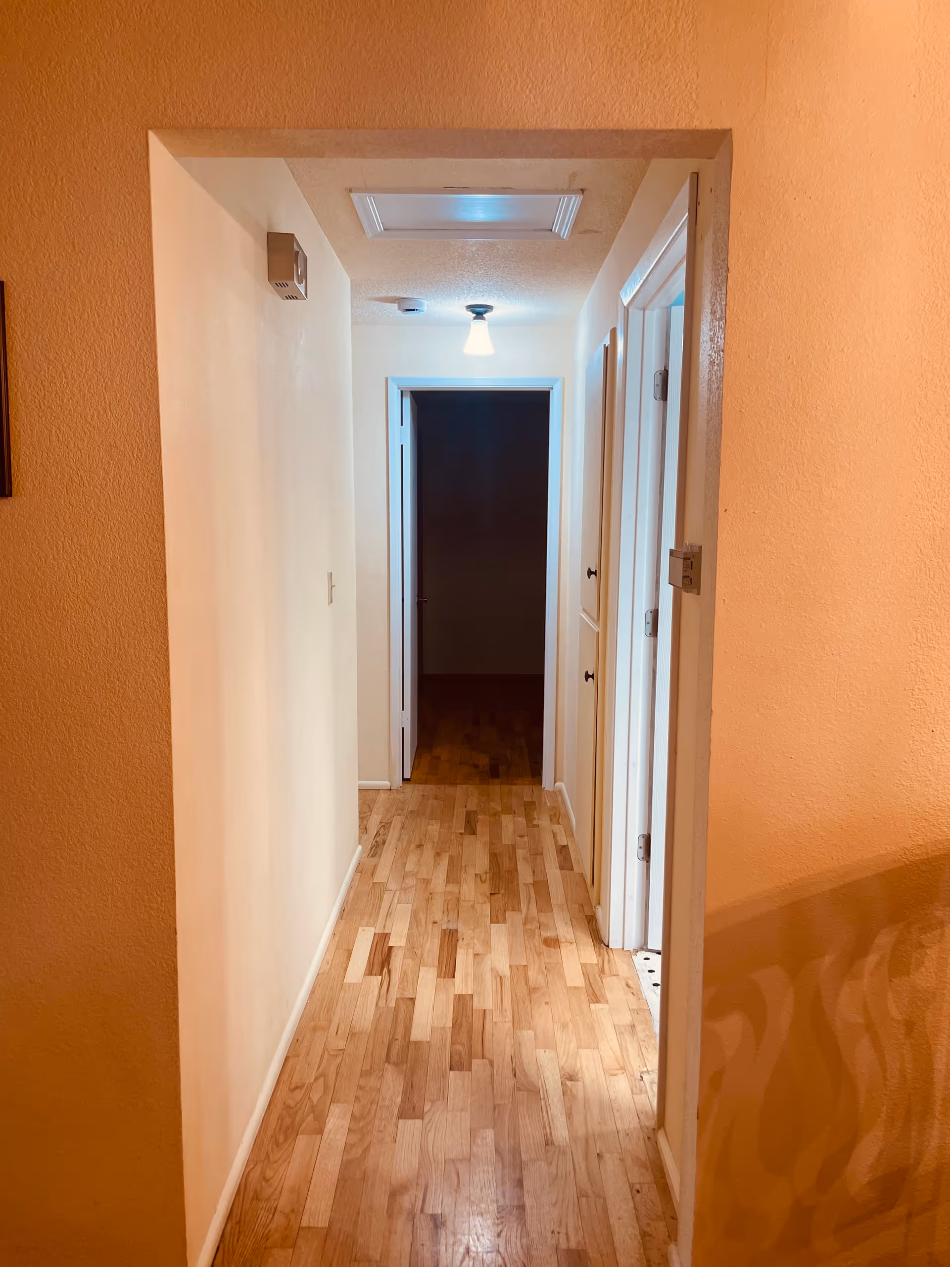 Hallway inside a senior living facility with beige walls and wooden flooring.