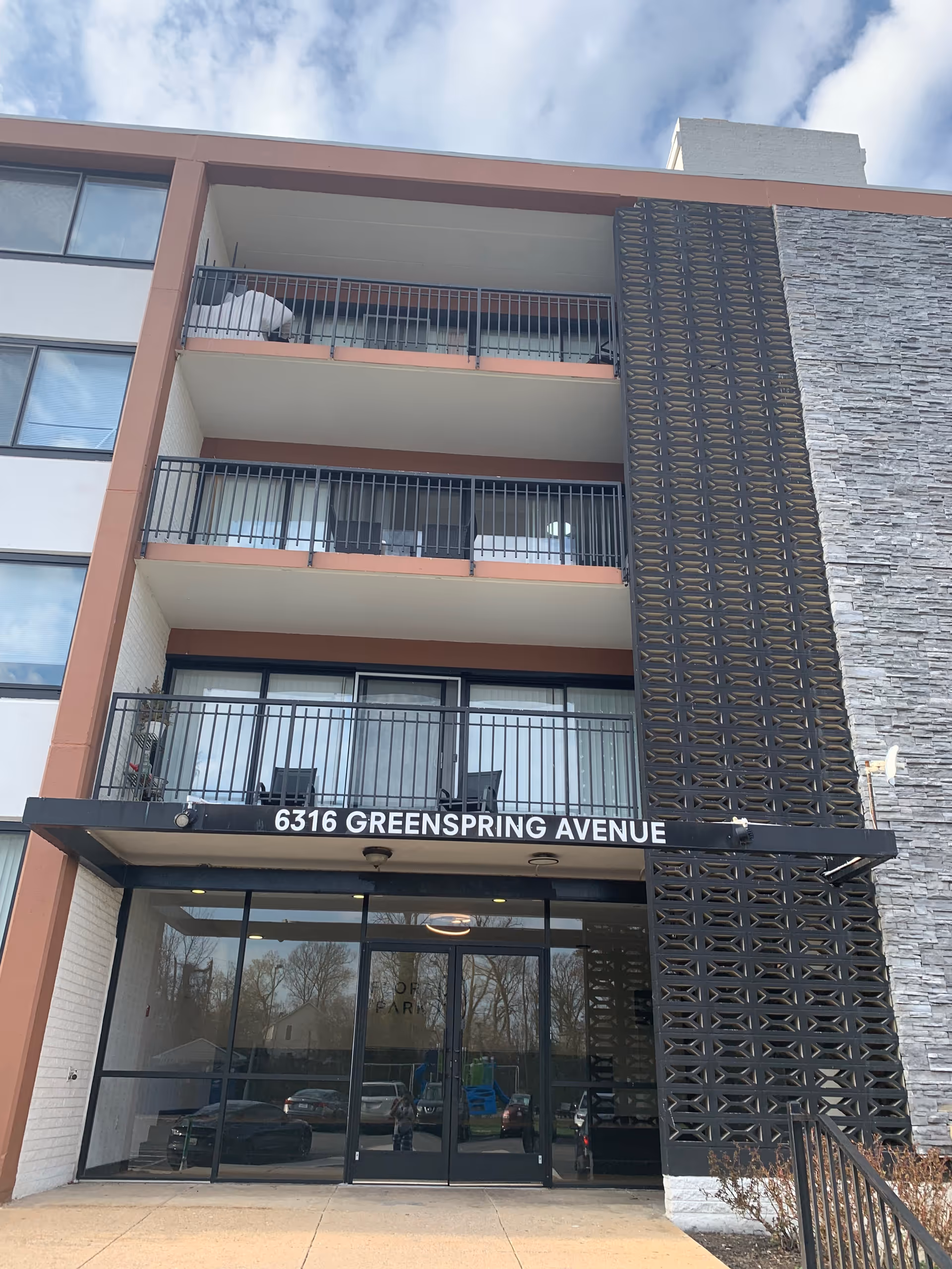Front of a modern senior building with balconies and a glass entrance.