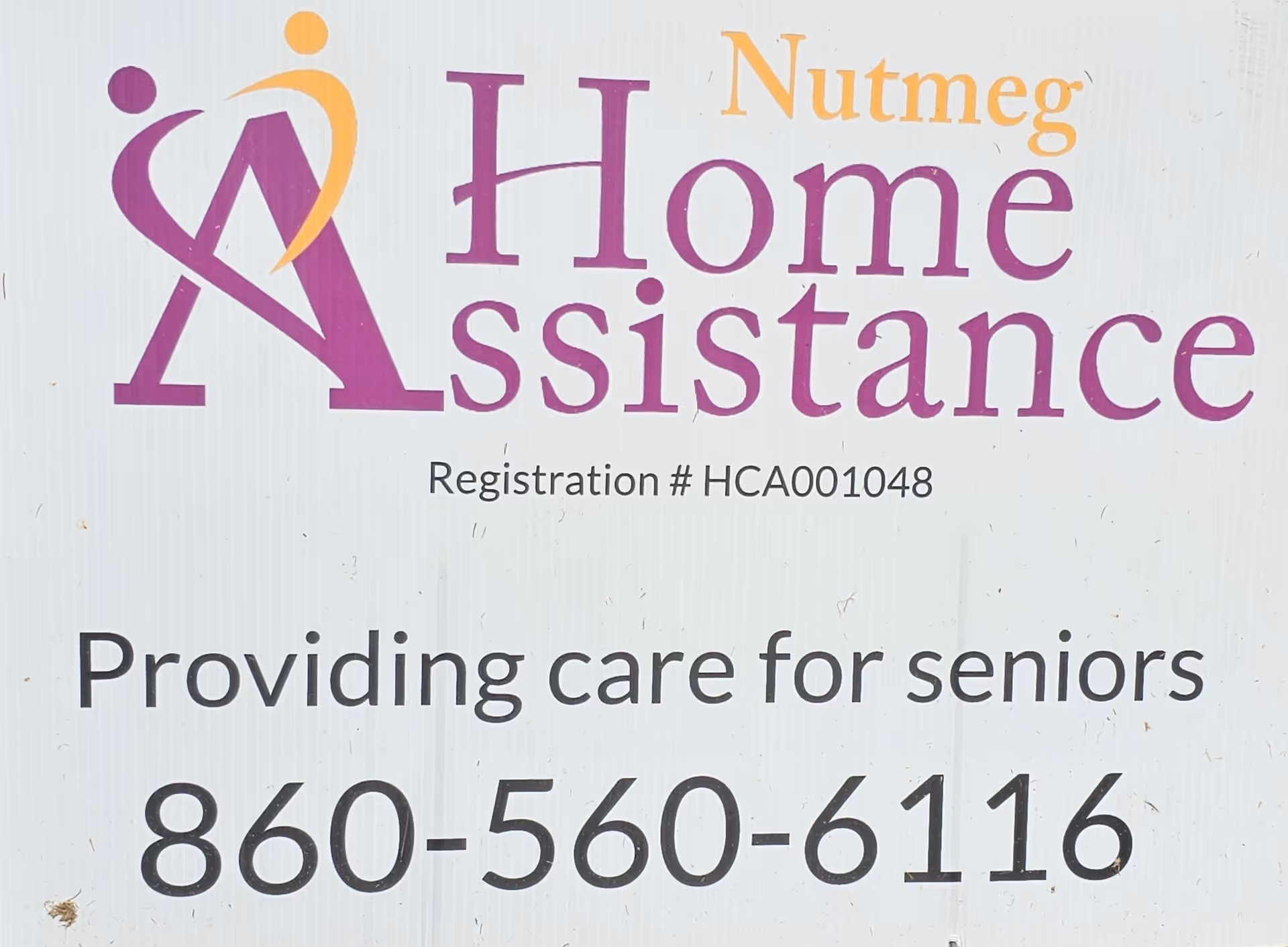 Exterior sign displaying Nutmeg Home Assistance logo, slogan, and contact number.