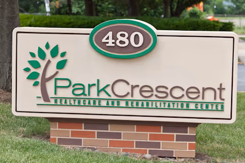Outdoor Park Crescent sign with tree logo and brick base near a grassy area.