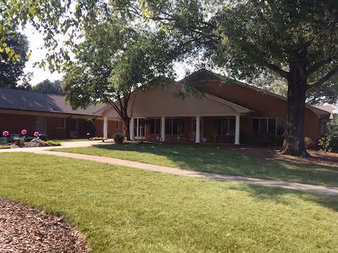 Front exterior view of Autumn Care of Biscoe with lawn and trees leading to the entrance