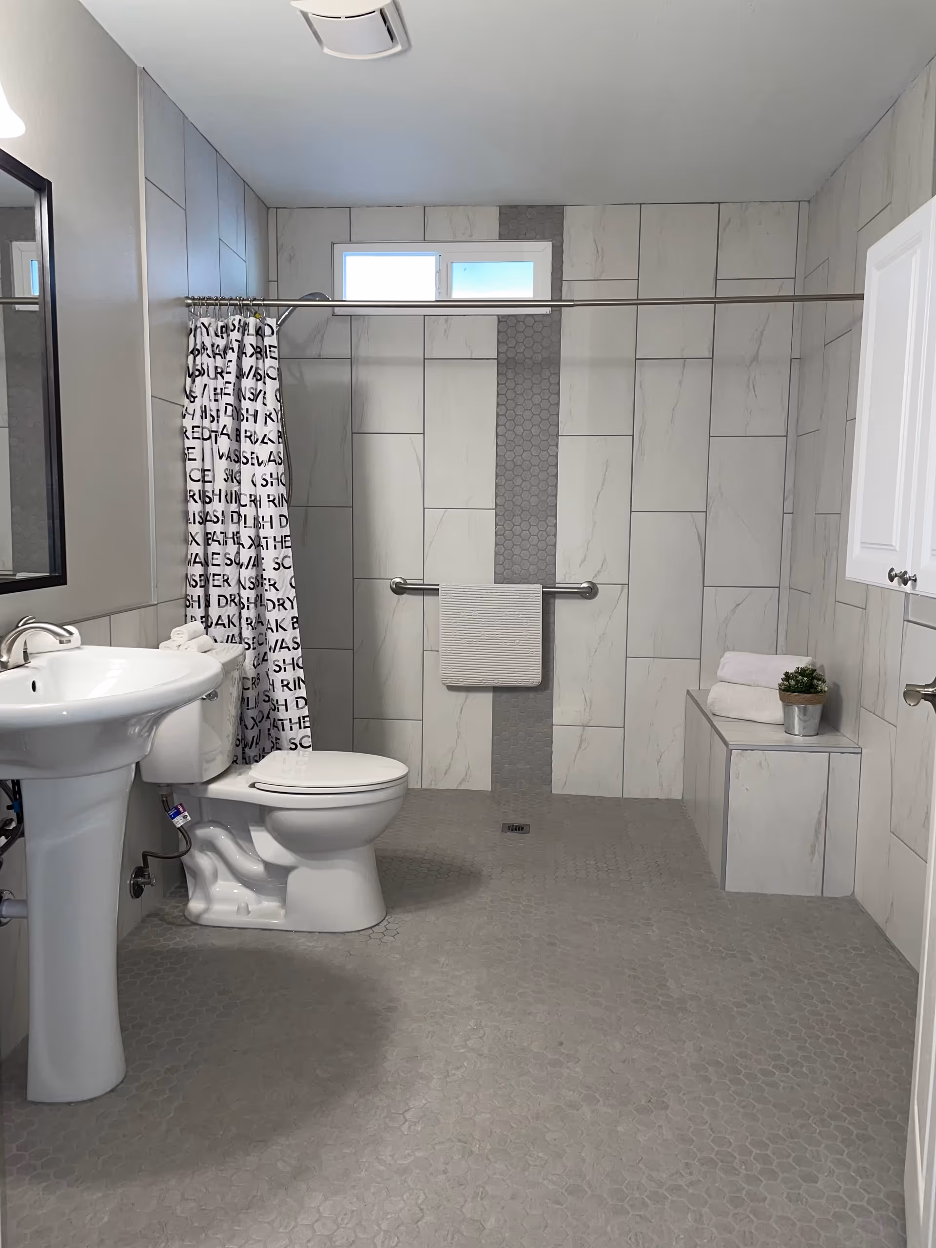 Accessible bathroom with a sink, toilet, and walk-in shower in a senior living facility.
