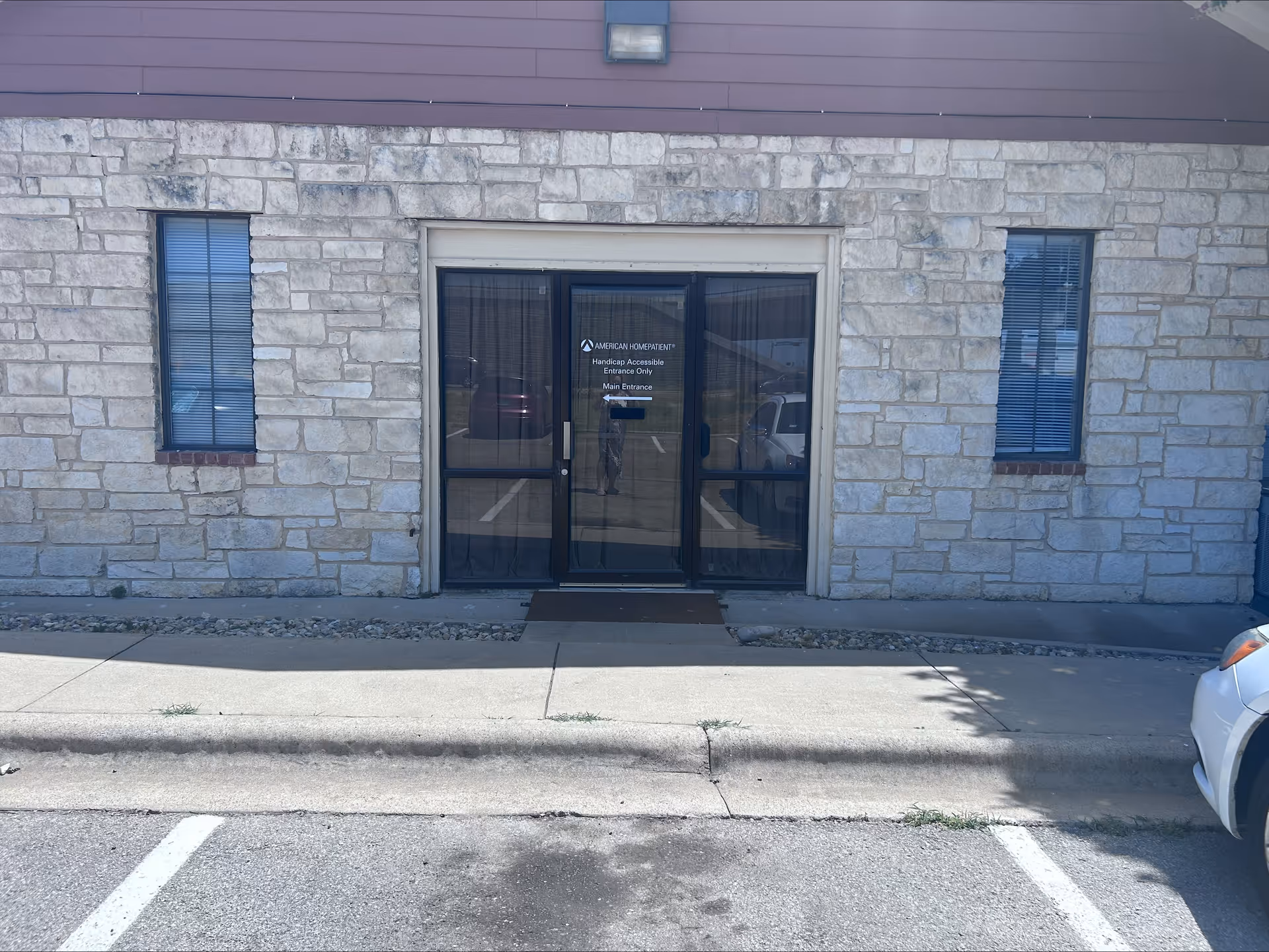 Stone exterior facility entrance with glass doors and two side windows.