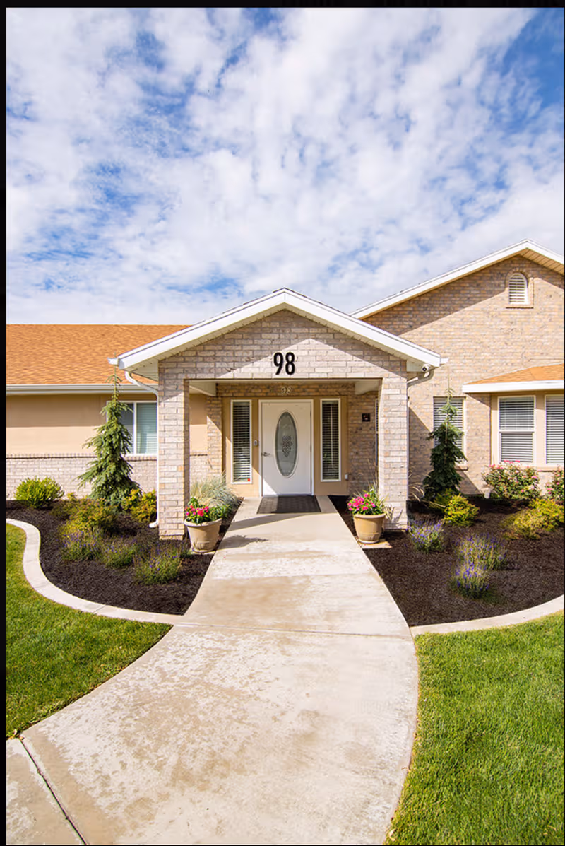 Front entrance of Rocky Mountain Care Spring Hollow with curved walkway and landscaping.