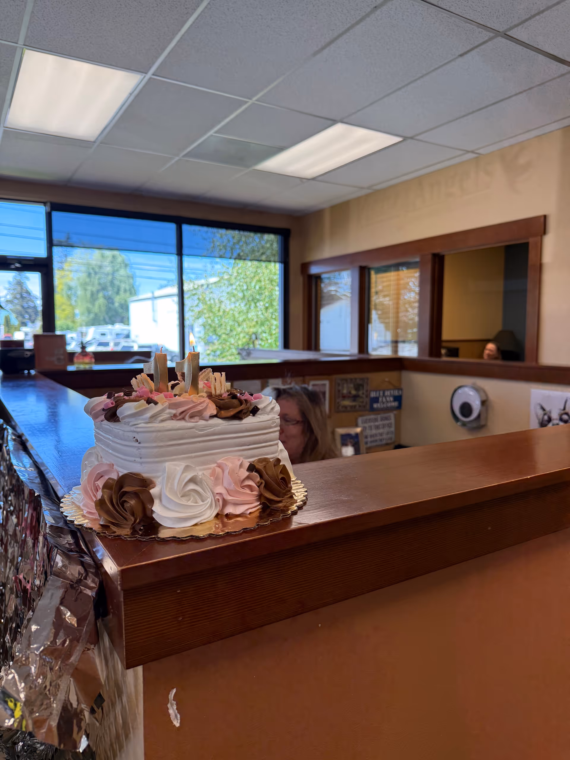 Cake with pink and brown frosting sits on a wooden reception counter.