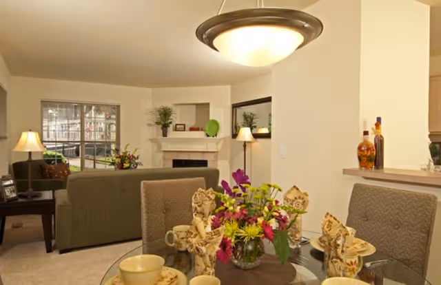 Cozy living area with a glass dining table, sofas, and a fireplace.