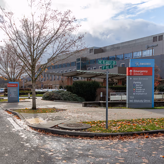 Exterior view of a Swedish medical building with street signs and a driveway.