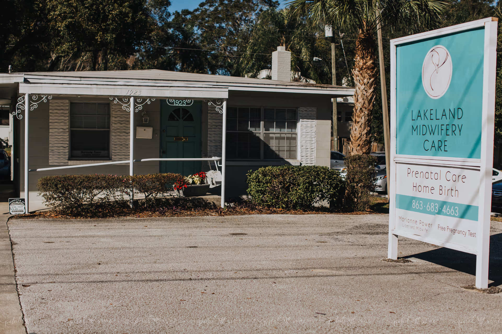 Single-story building with a turquoise door and a large Lakeland Midwifery Care sign outside.