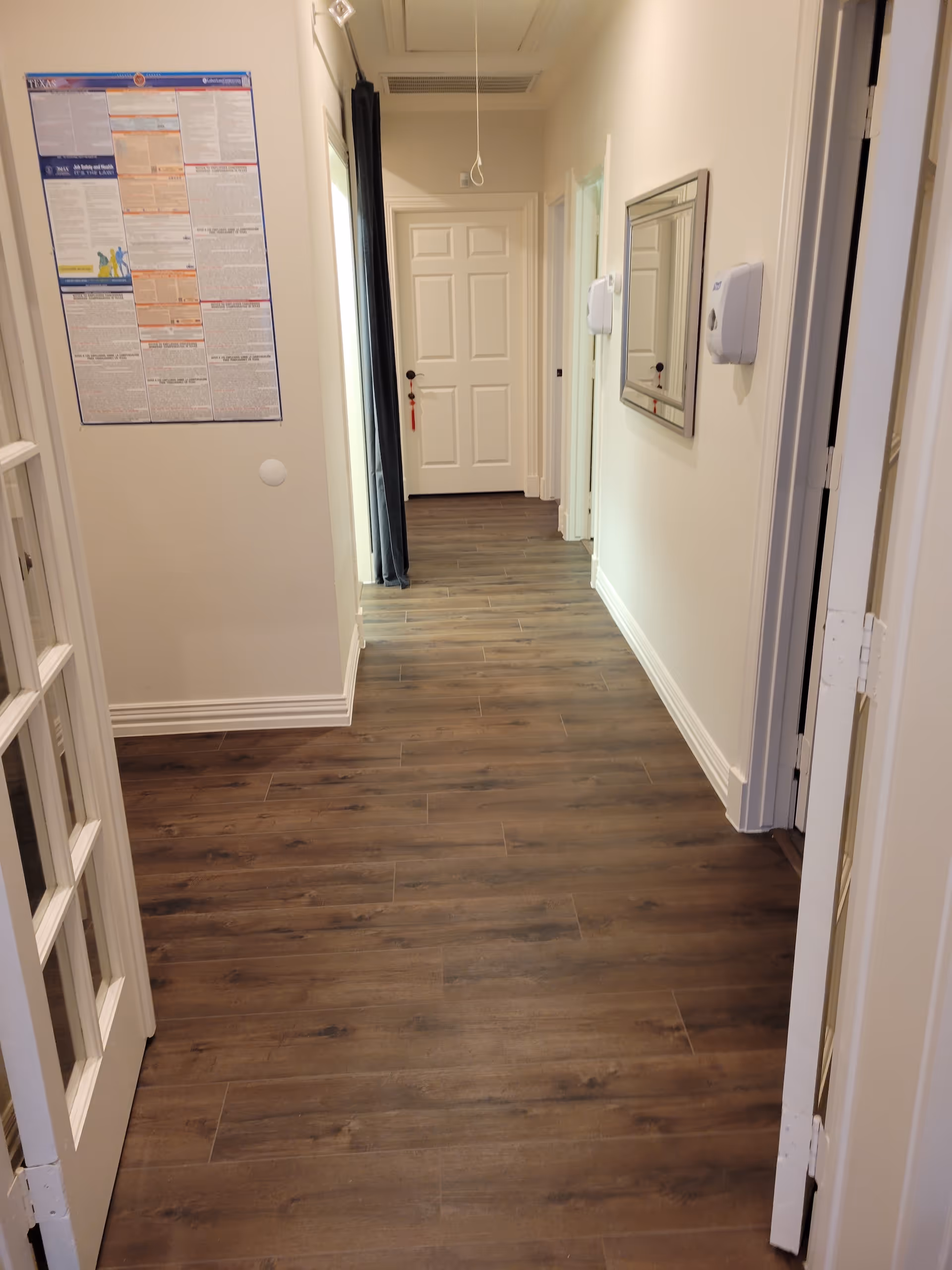 Interior hallway in a senior living facility with wooden flooring and closed doors.